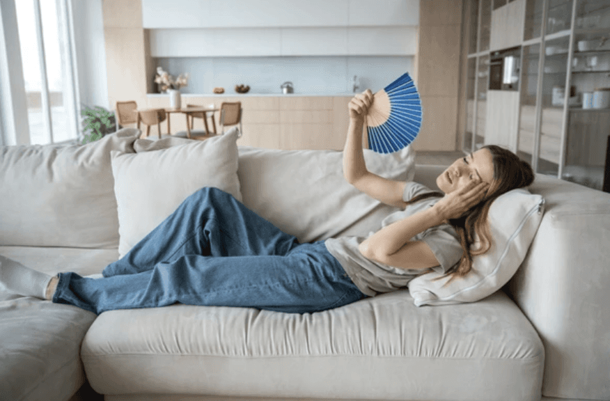A woman on her coach, feeling the summer heat, before calling for insulation and roofing weatherford TX services