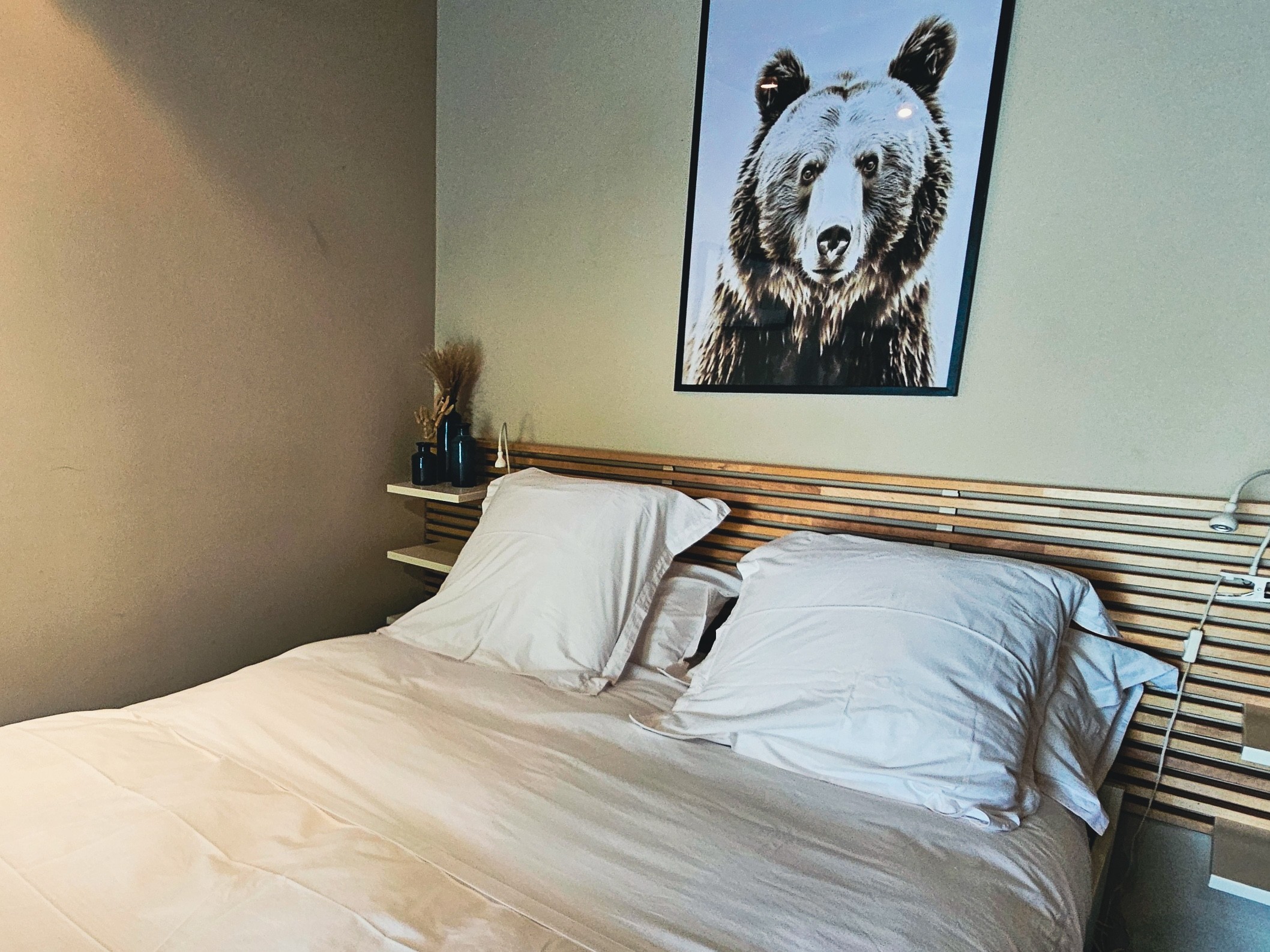 Cadre d'ours au-dessus d'un lit blanc.