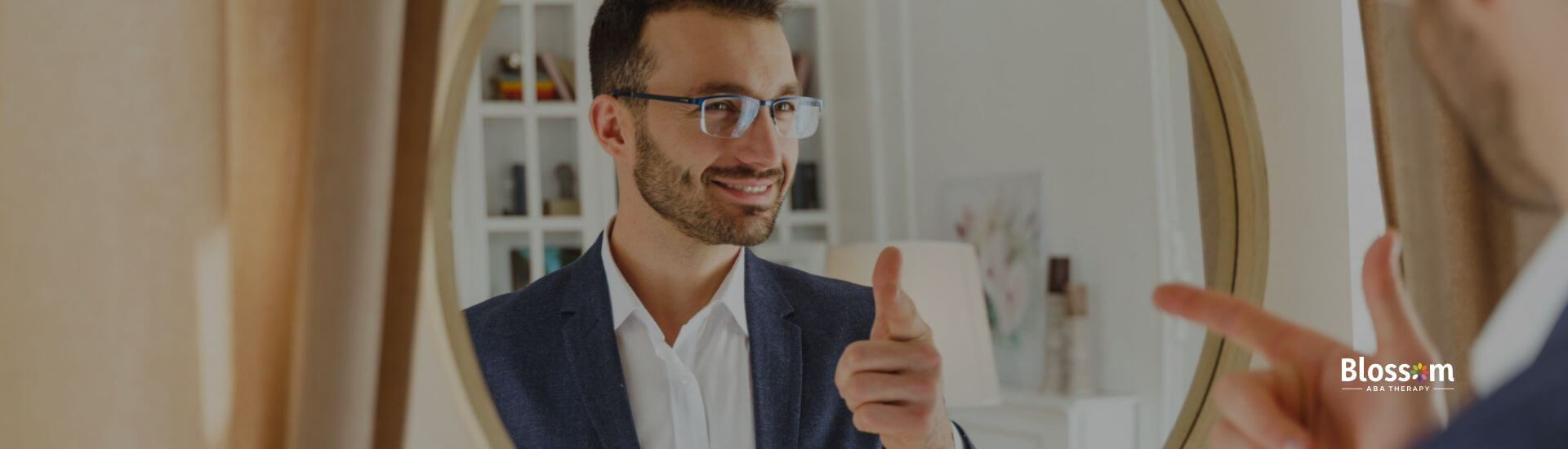 Man with autism smiling and pointing at his reflection in a round mirror.