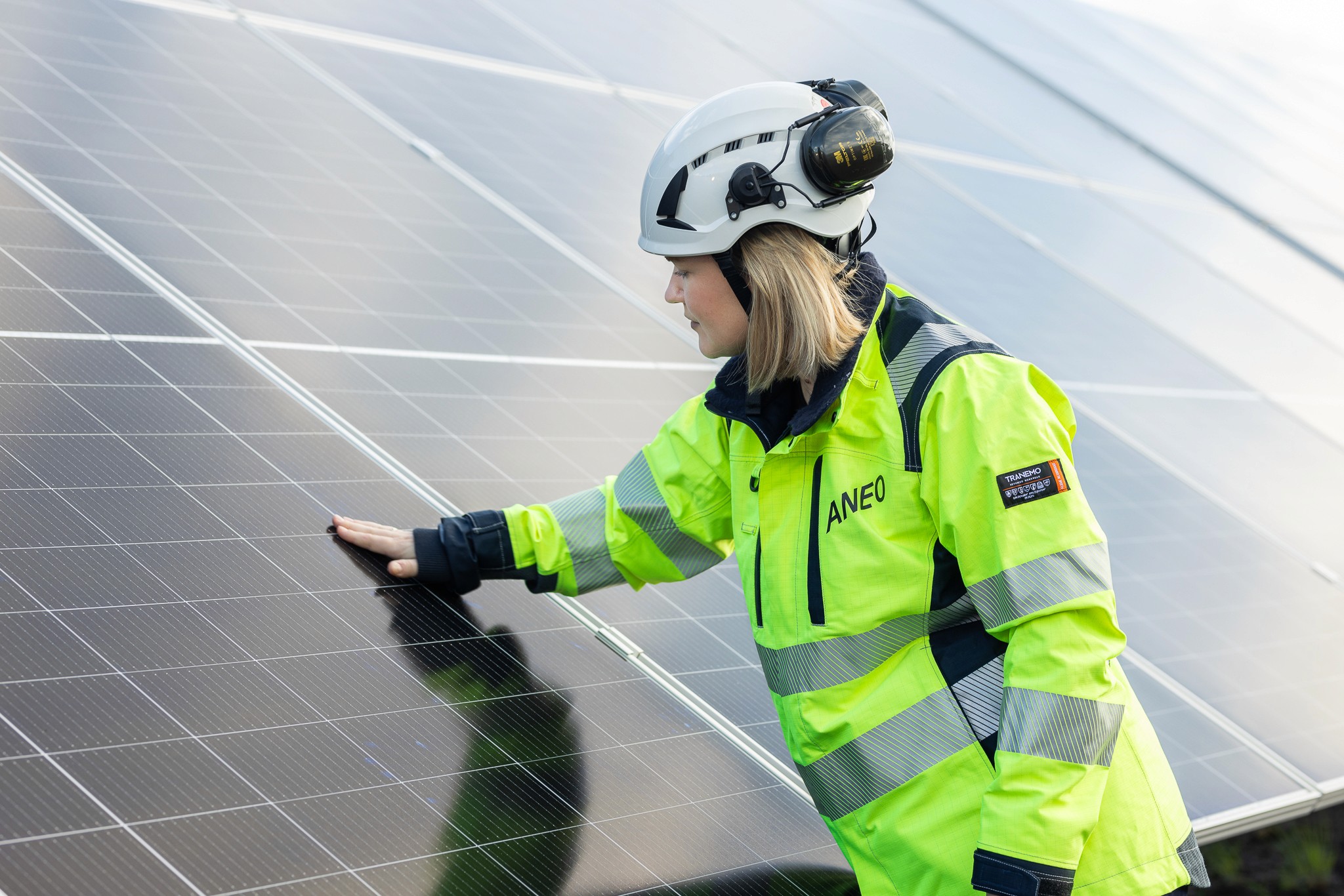 Närbild av en Aneo-anställd som känner på de nyinstallerade solpanelerna i Henja solpark