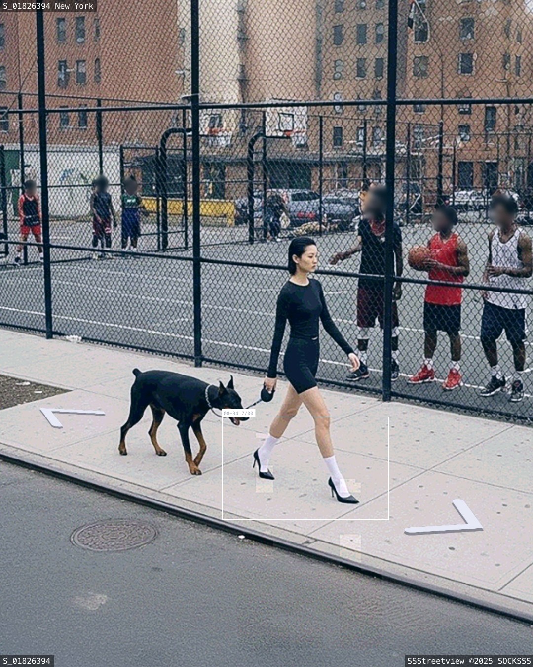Une femme avec des chaussettes blanches marche sur le trottoir avec son chien devant des joueurs de basket à New York