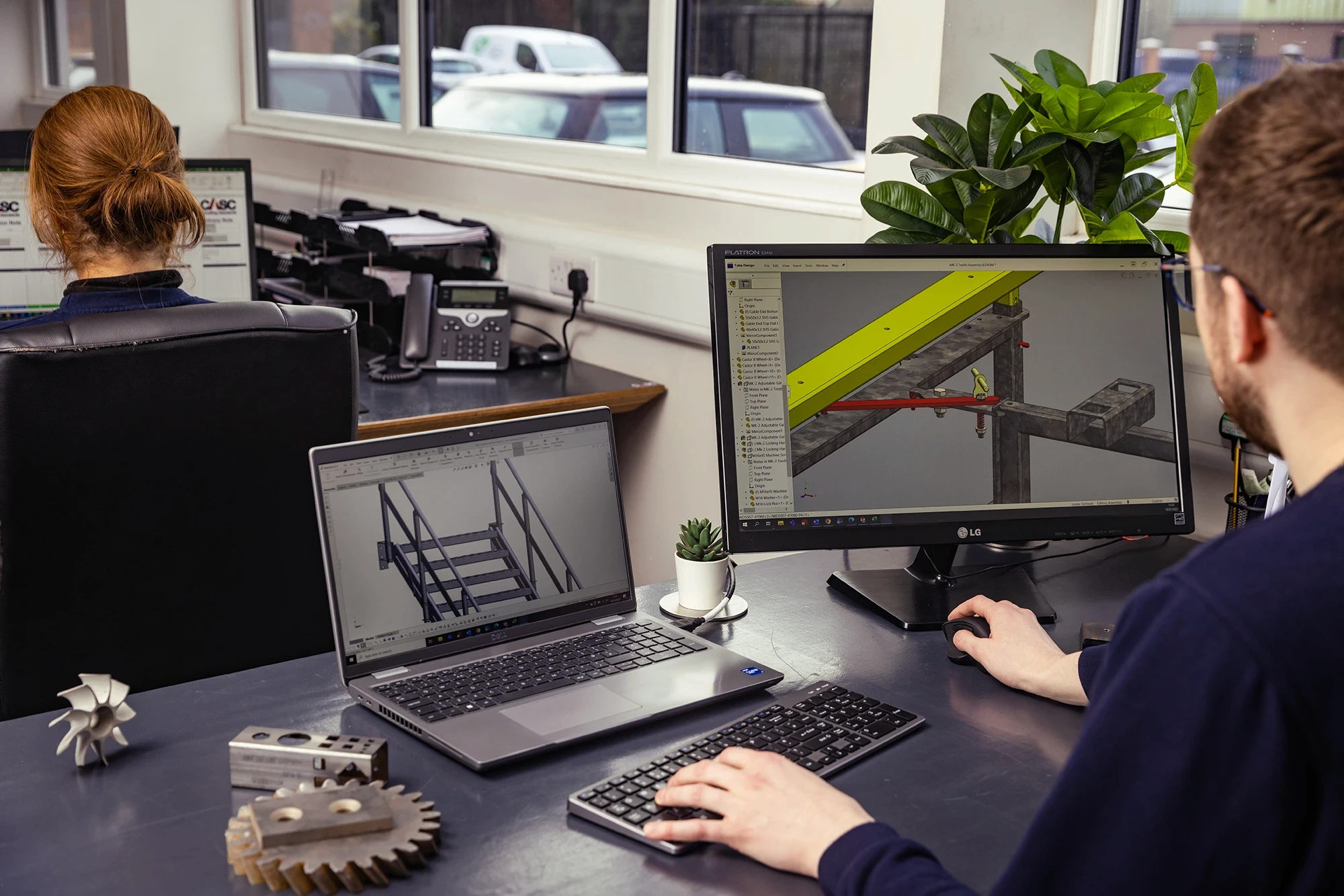 Engineers working at desks using CAD software to design manufactured components.