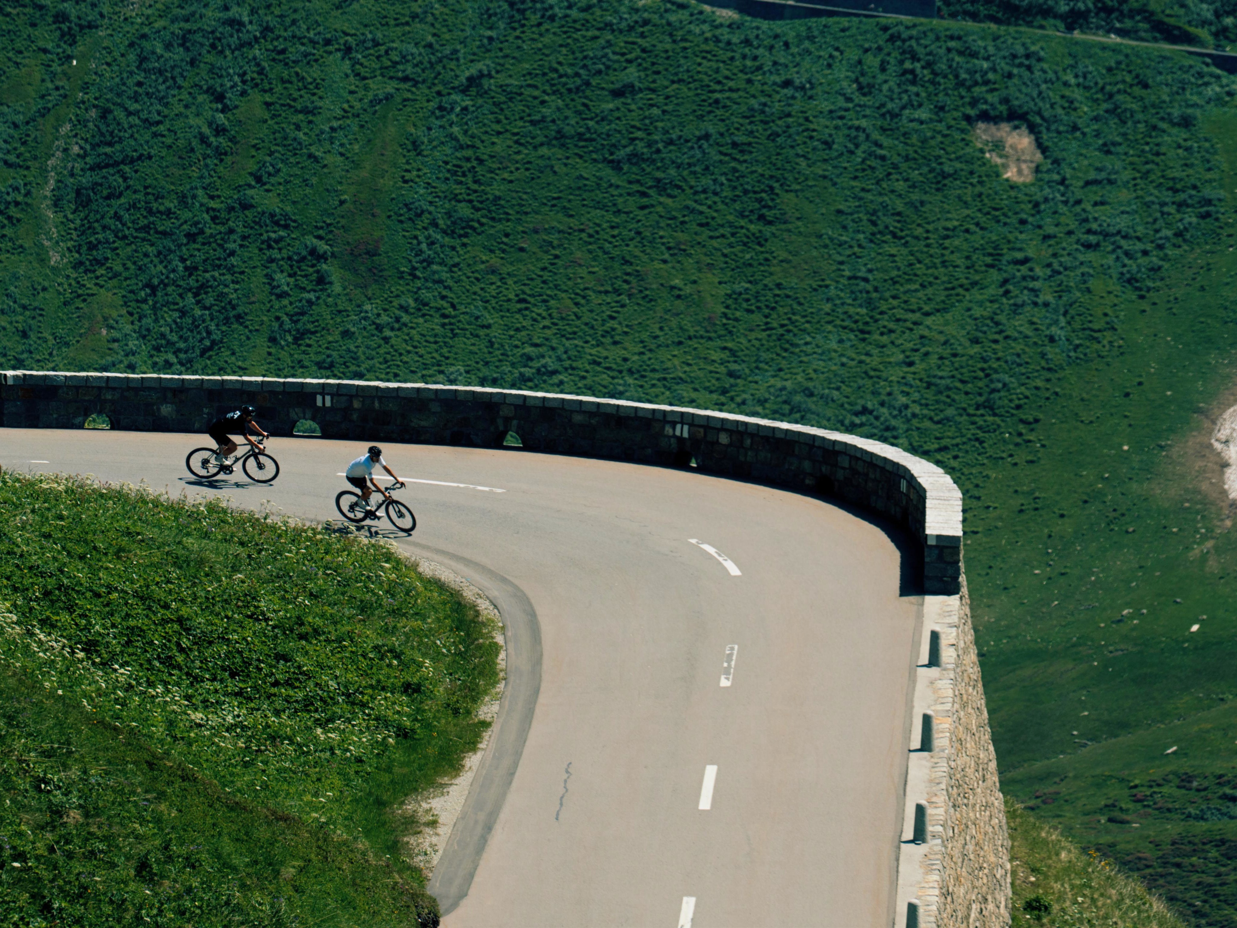 Two cyclists descending a mountain road in the Swiss Alps
