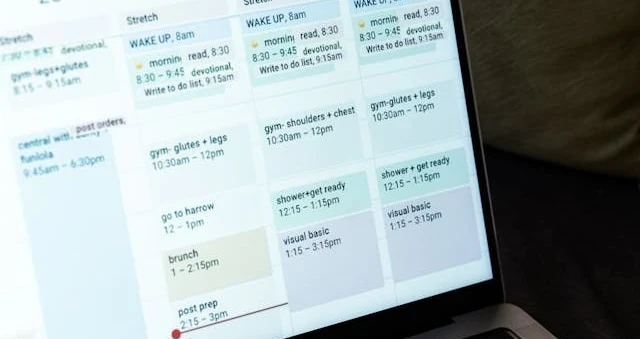 Laptop exibindo um calendário mensal com compromissos, com as mãos de uma pessoa digitando