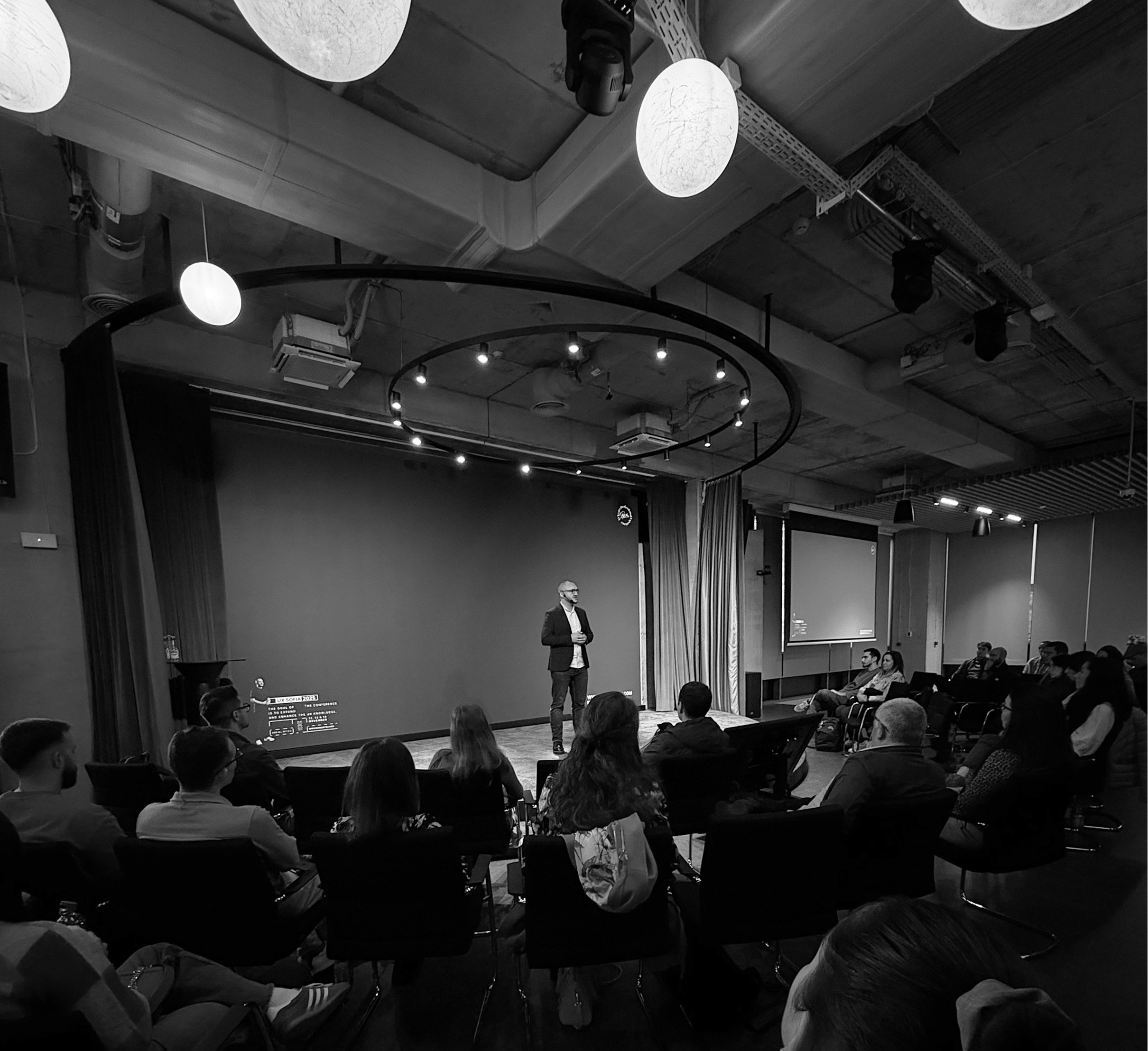 Image of A senior UX designer presents to an audience on UX design and strategy in a conference room.