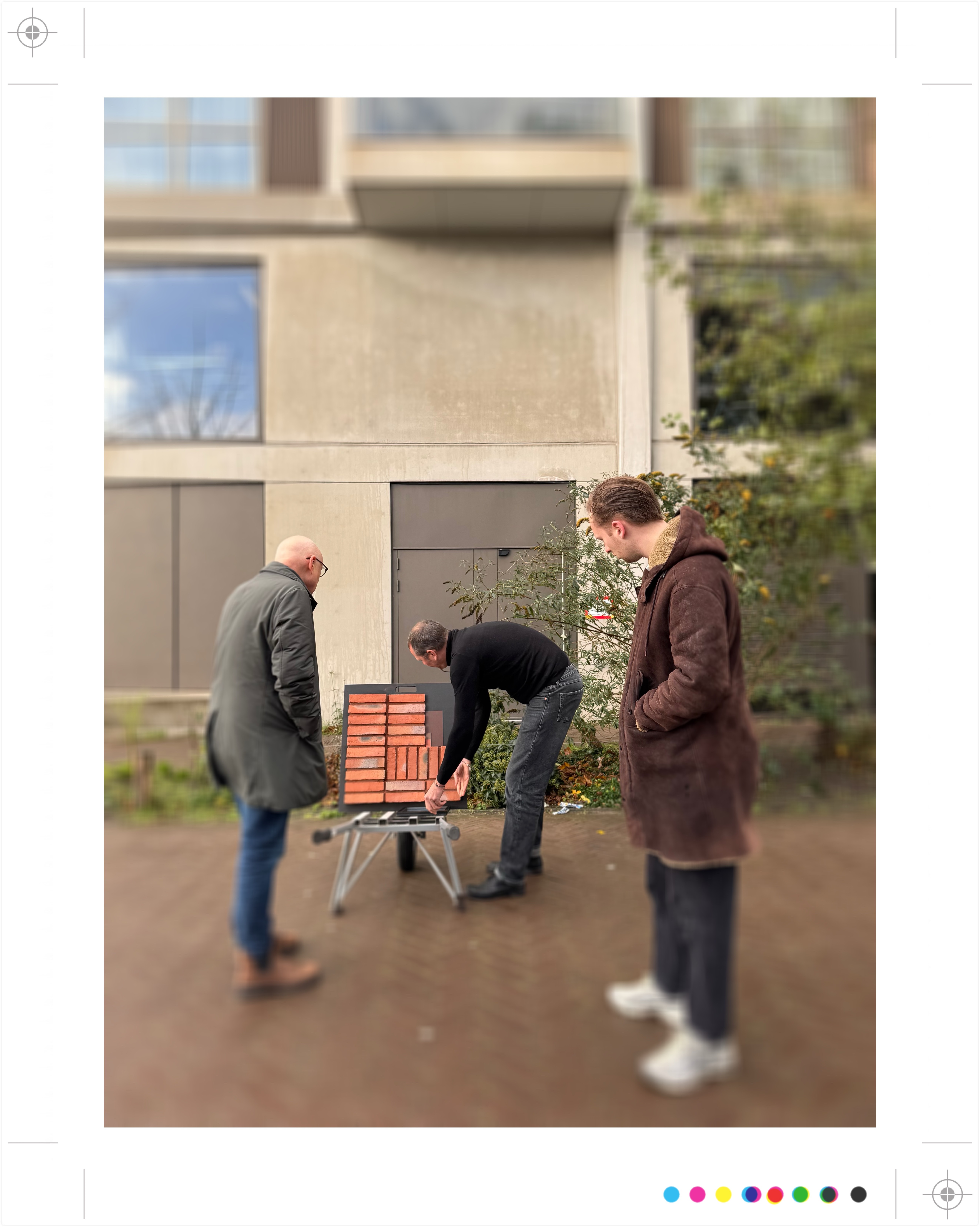 Drie mensen bekijken baksteenstalen op een display buiten een gebouw.