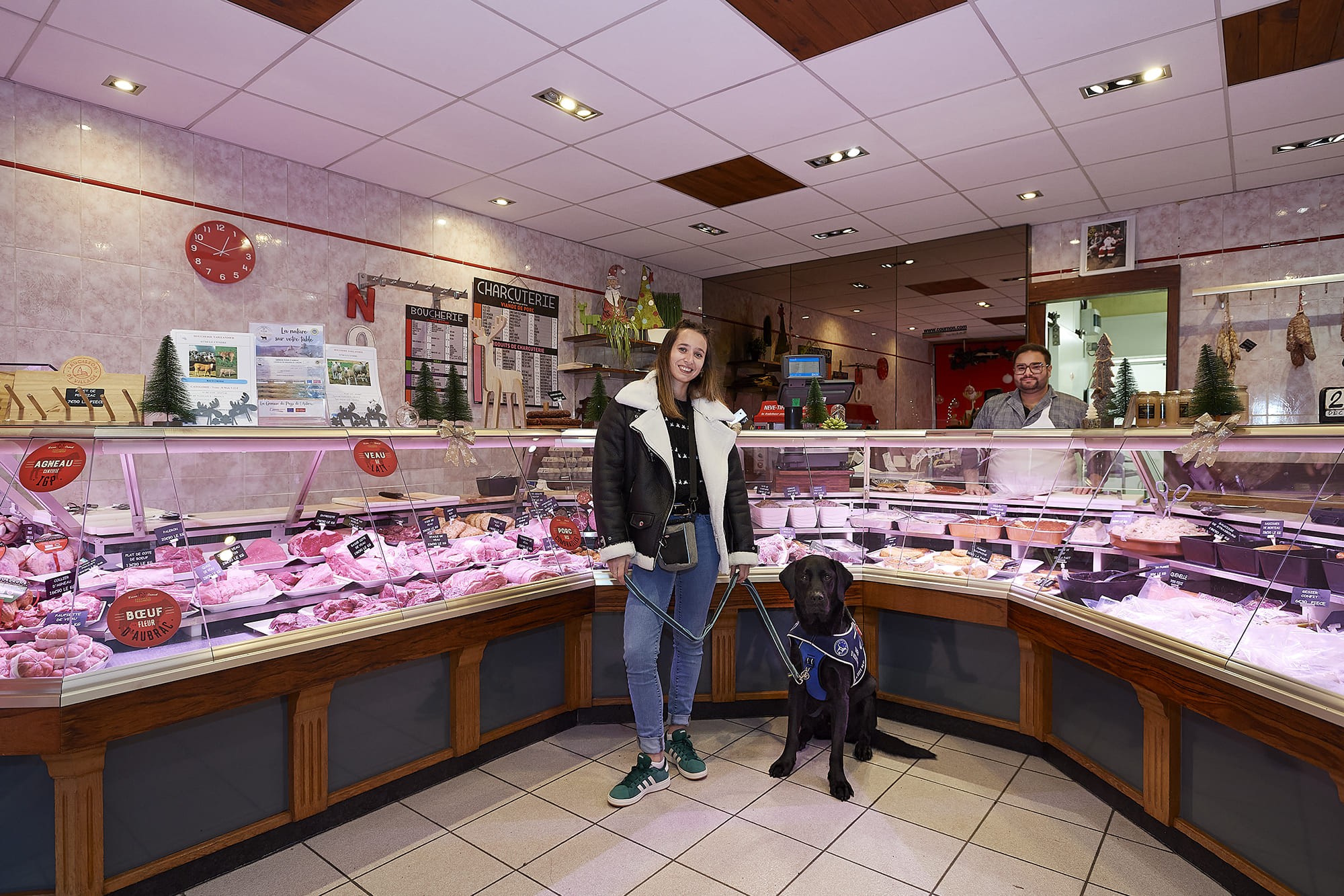 Ophélie accompagnée de son chien d’assistance Trendy, photographiées par Frédéric Bourcier à la boucherie Taillandier (Maison Dumont) et à la supérette Vival au Cendre dans le cadre d’un reportage documentaire social pour Handi’Chiens.