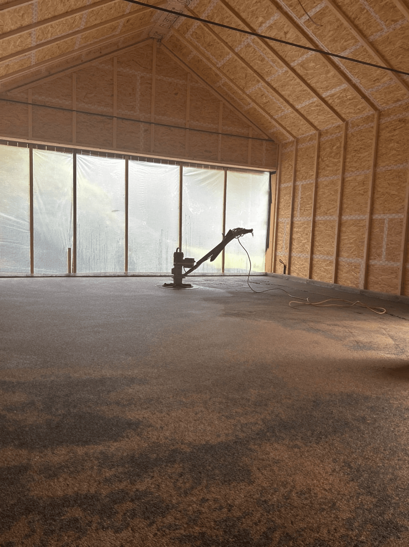 In einer Werkstatt mit Betonboden, einer Schleifmaschine sowie Wänden und Decke aus Holz.
