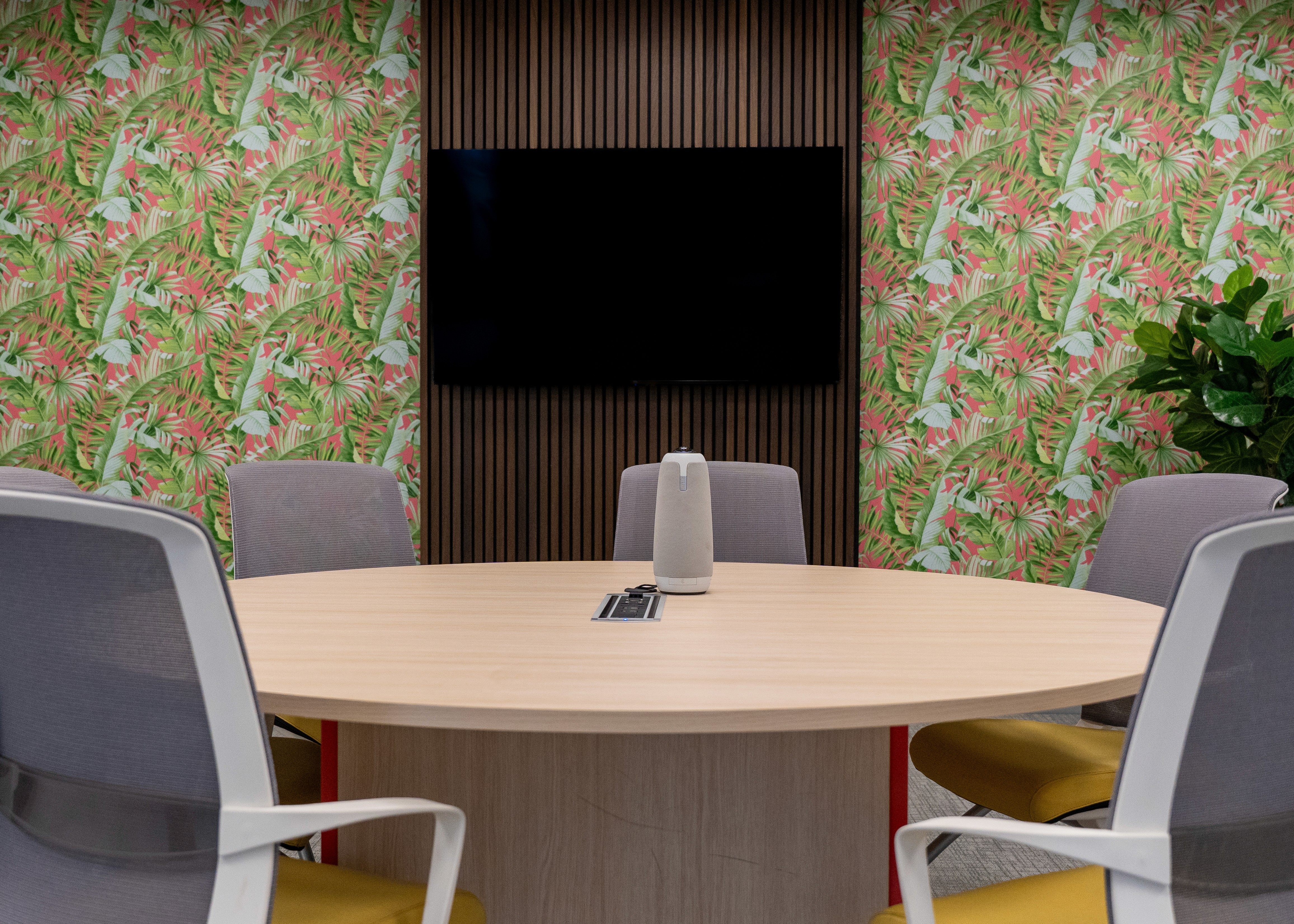 Spacious open-plan office with red accent furniture, indoor trees, and floor-to-ceiling windows