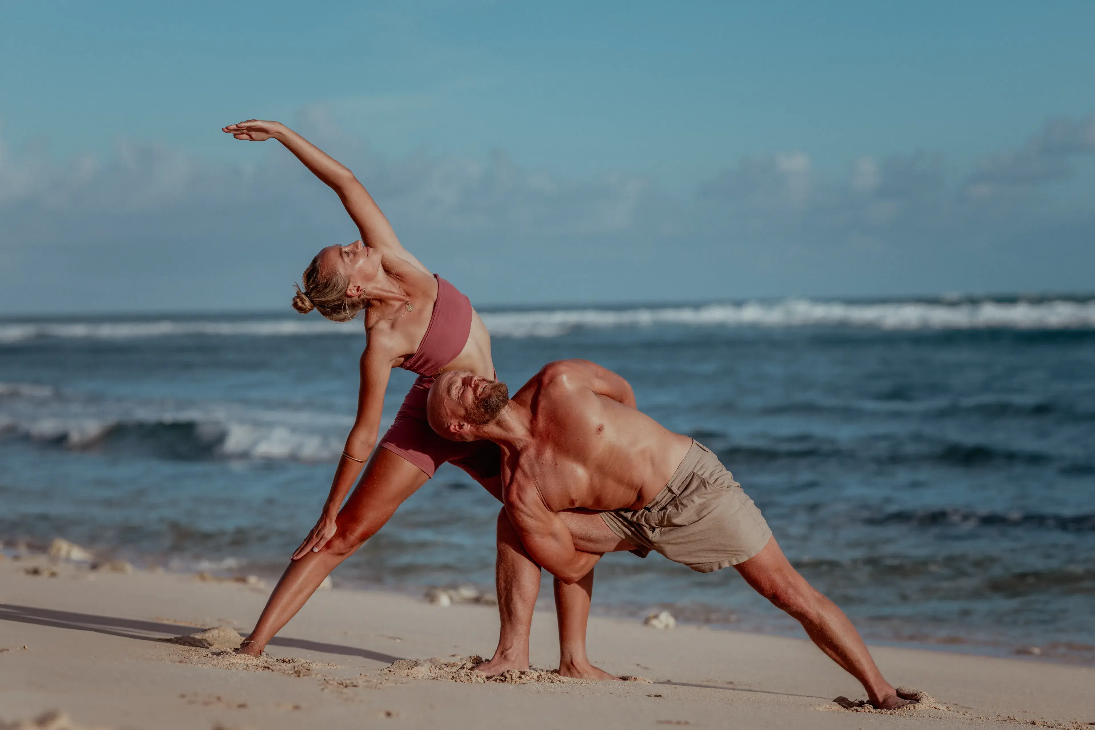 Students practicing partner yoga on the beach during the 200-hour multi-style yoga teacher training program in Bali