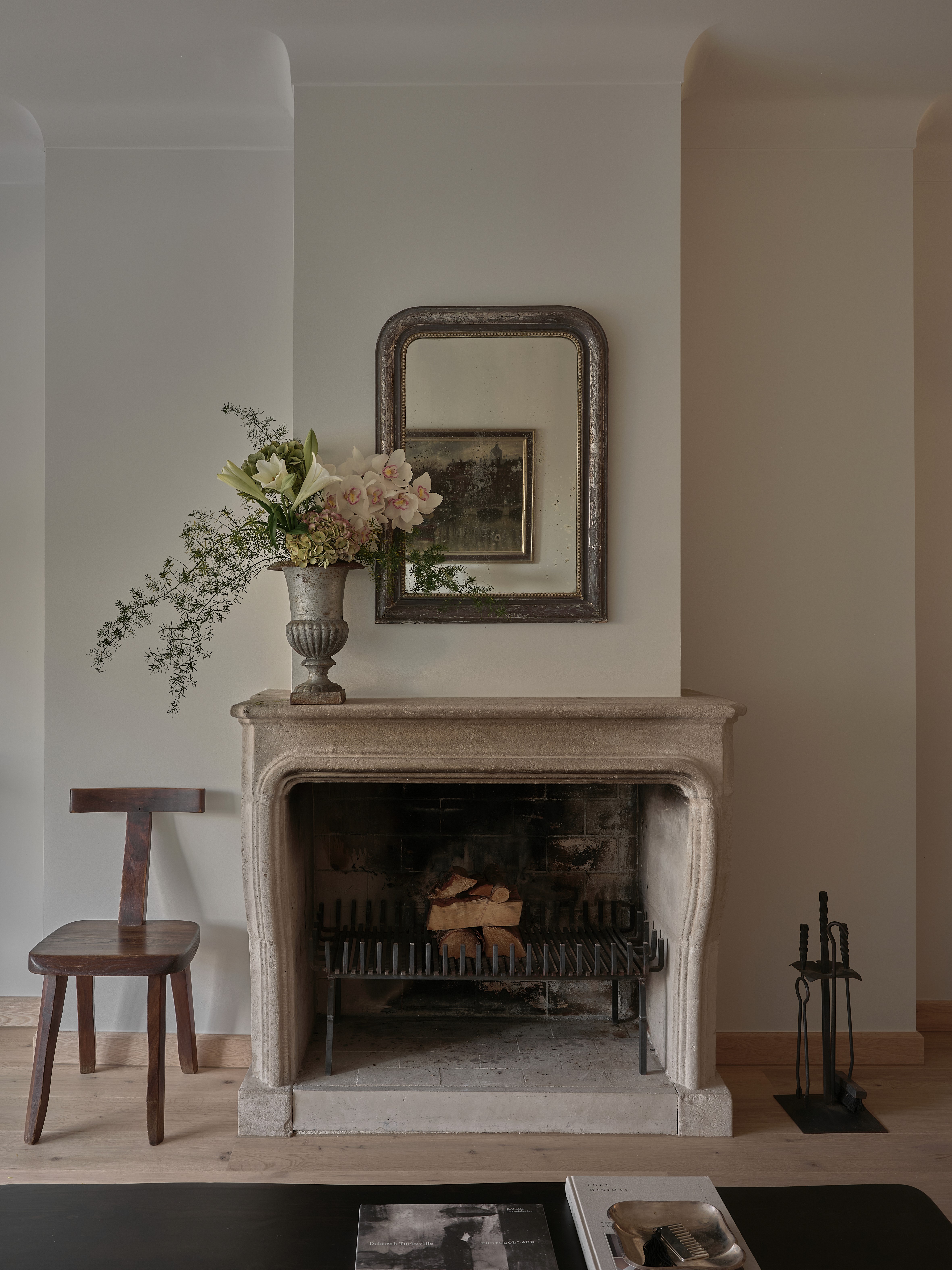 Original stone fireplace with antique vase, greenery arrangement, and iron fire tools
