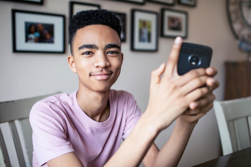 Confident teenager holding his phone.