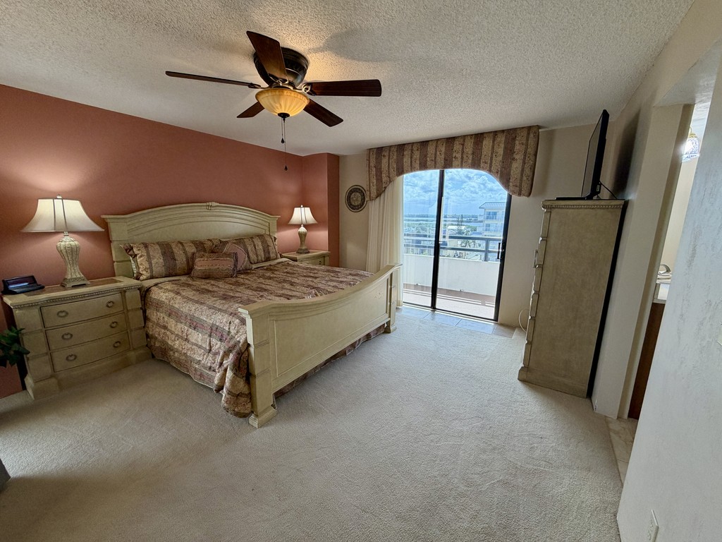 Bedroom with a coral accent wall and balcony door, Unit 507 at The Ashley, a vacation rental in Daytona Beach Shores