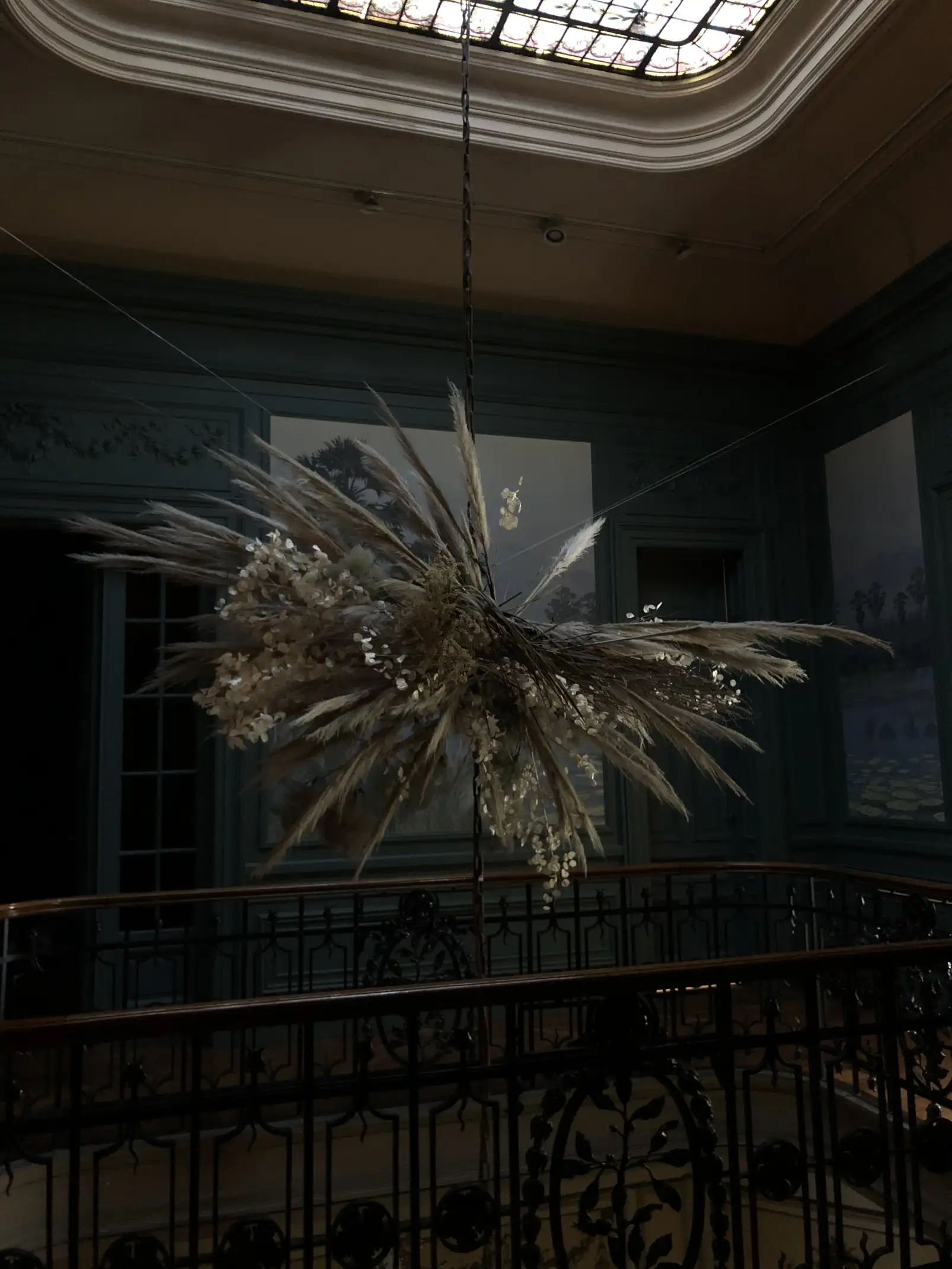 Instalación floral suspendida con pampas y hojas secas en ambiente clásico para proyectos de decoración artística.