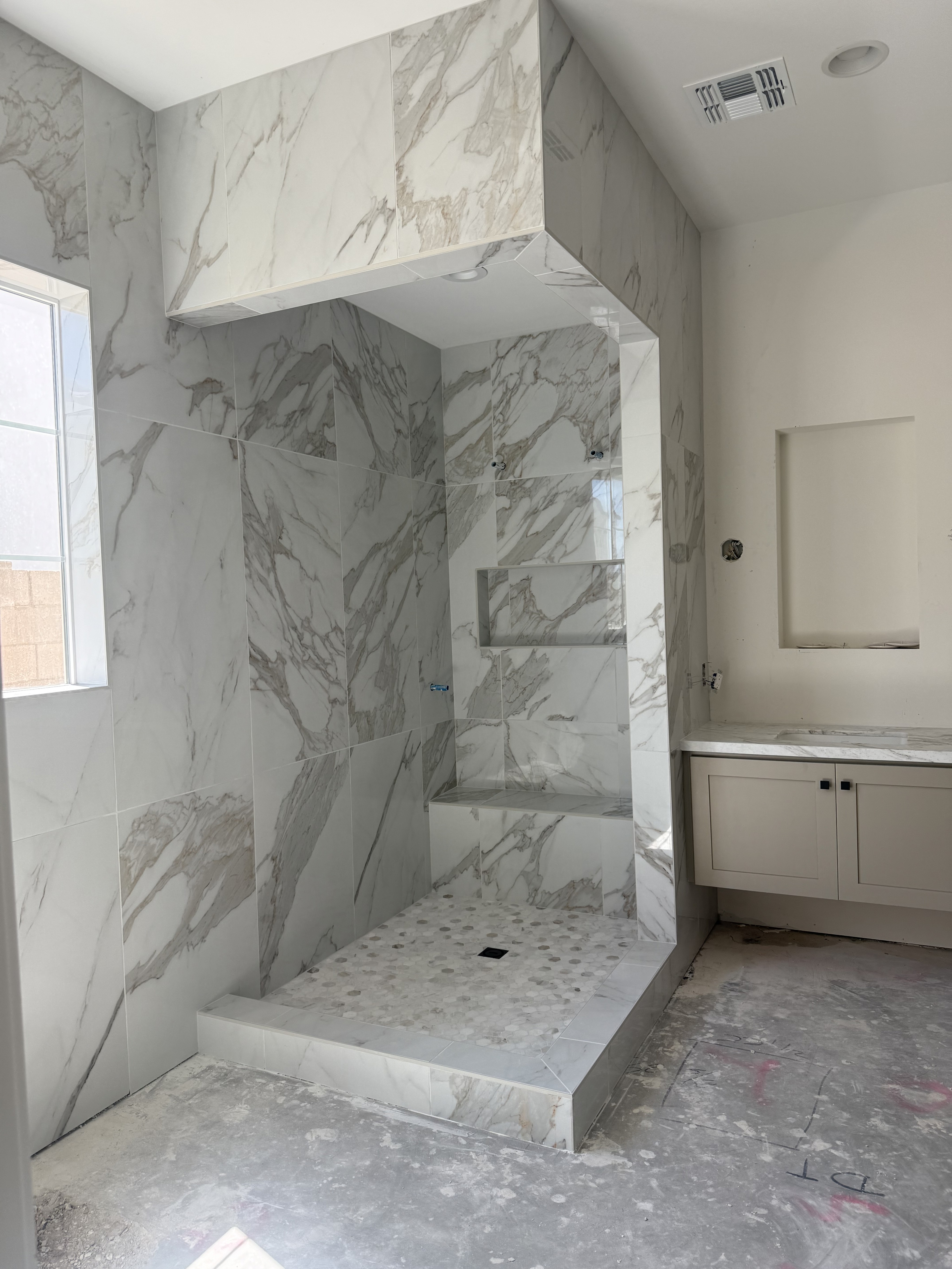Luxurious bathroom vanity area with a dramatic wall featuring large format natural stone tiles in varying earthy tones and complex veining, serving as a striking backsplash above a double sink vanity.