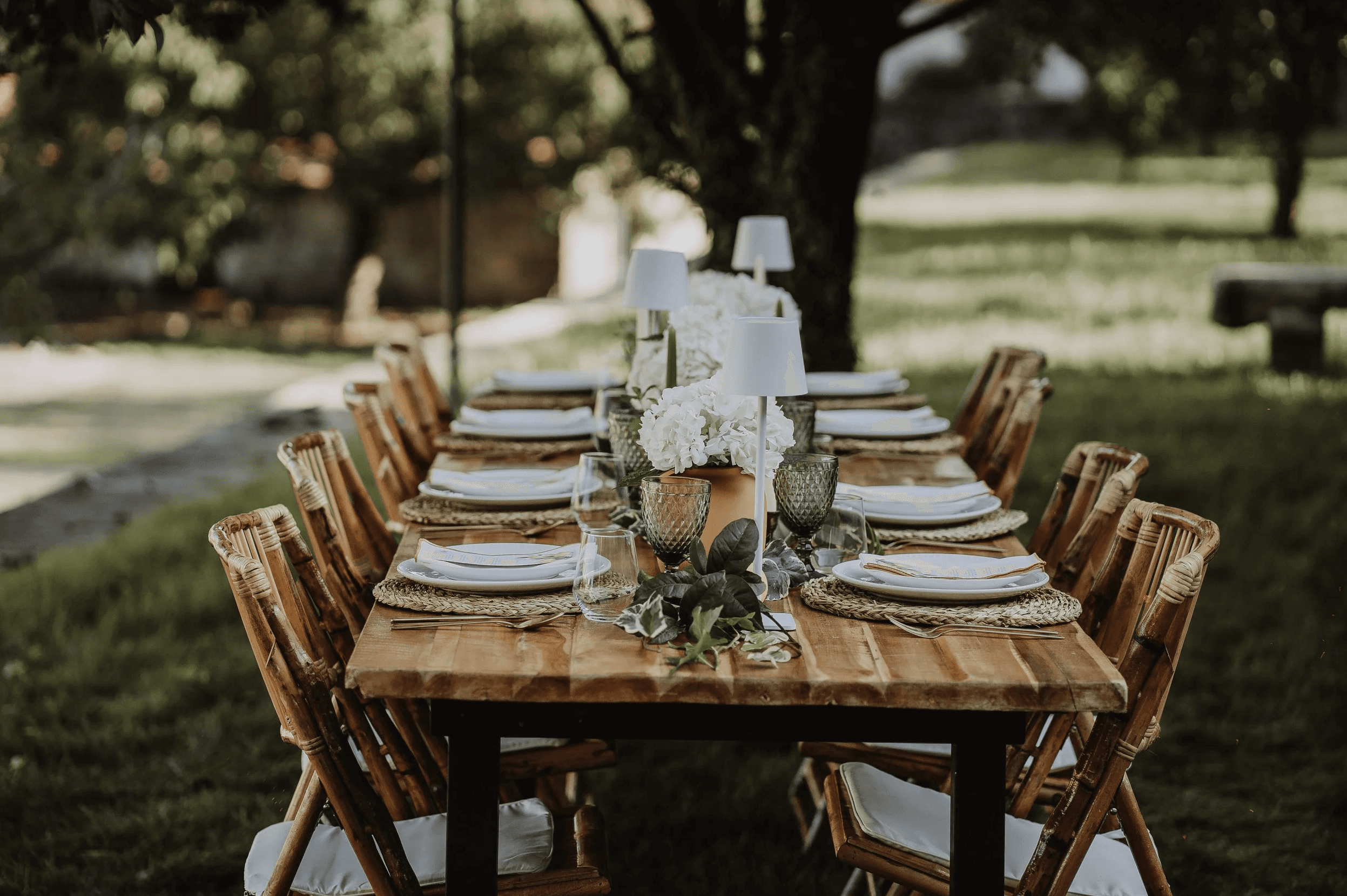 A beautifully set dining table with white tablecloth, cutlery, and fresh greenery in a cozy, well-lit space.