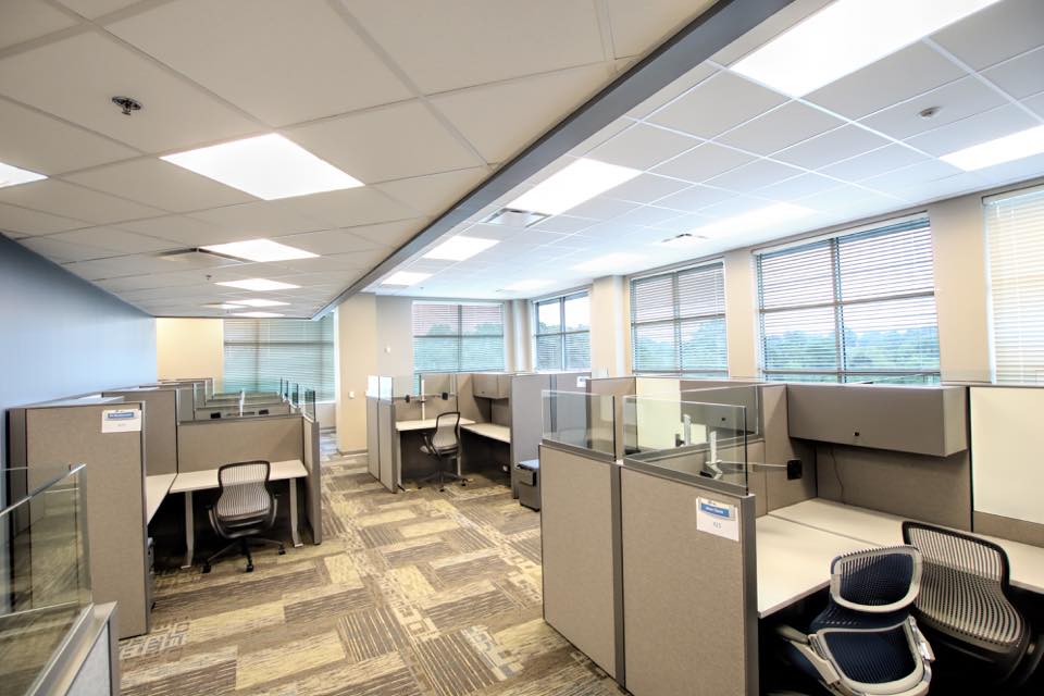A modern office space featuring cubicles, bright lighting, and a clean, organized layout.