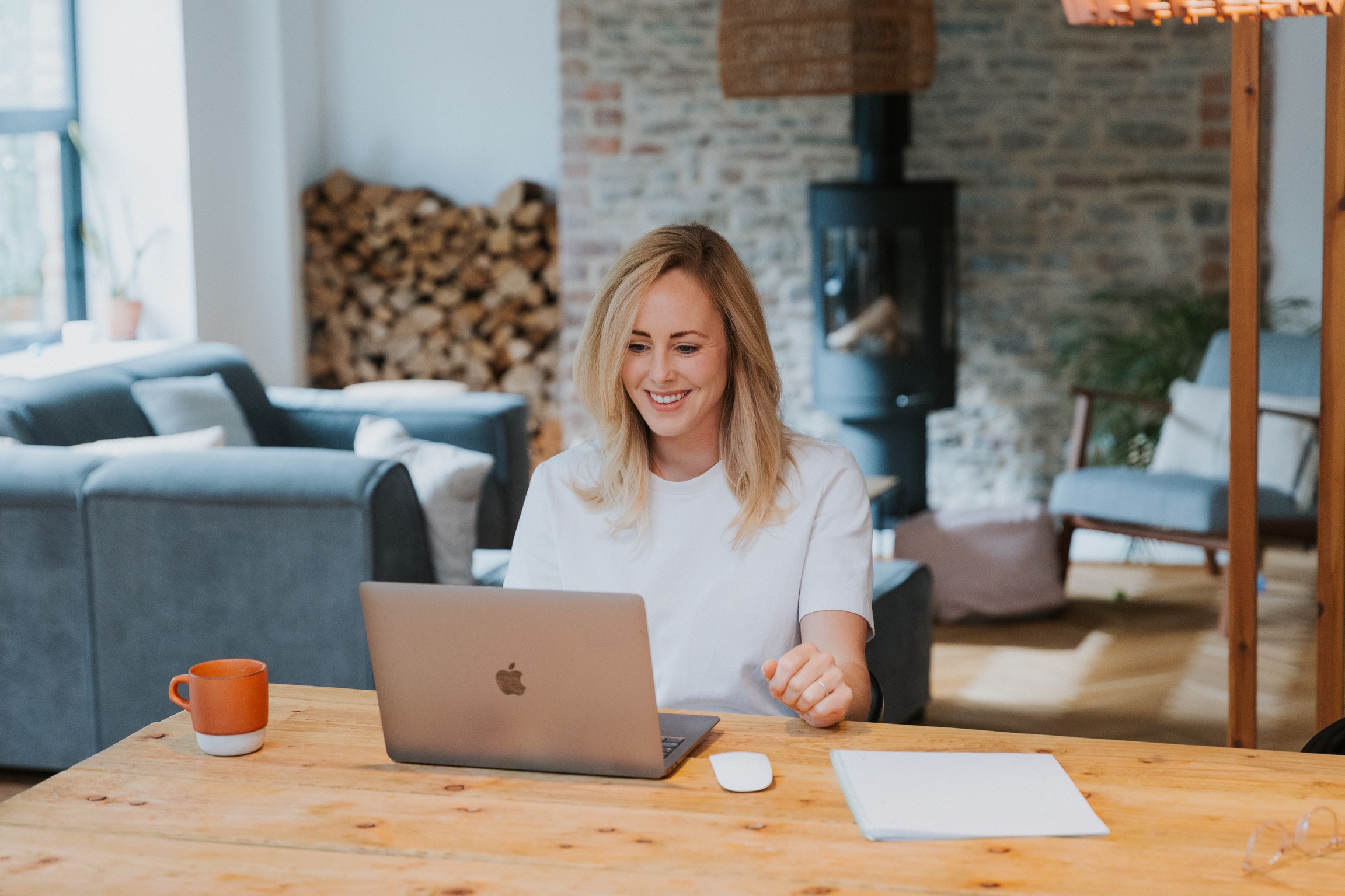 Photo for figurative purposes of a smiling young woman, taking notes while consulting her laptop computer.