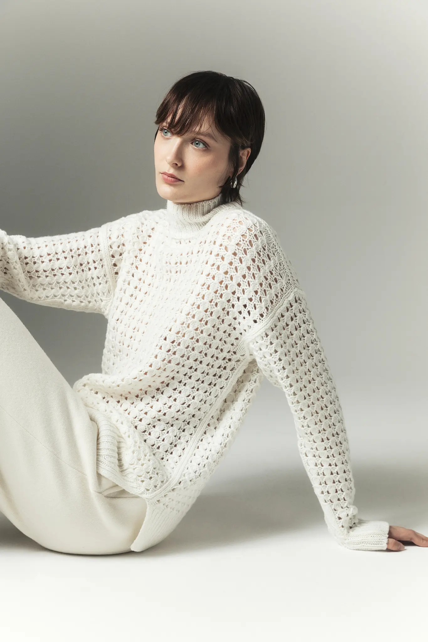 Woman wearing white open-knit cashmere sweater – Aida Barni FW25/26 collection.