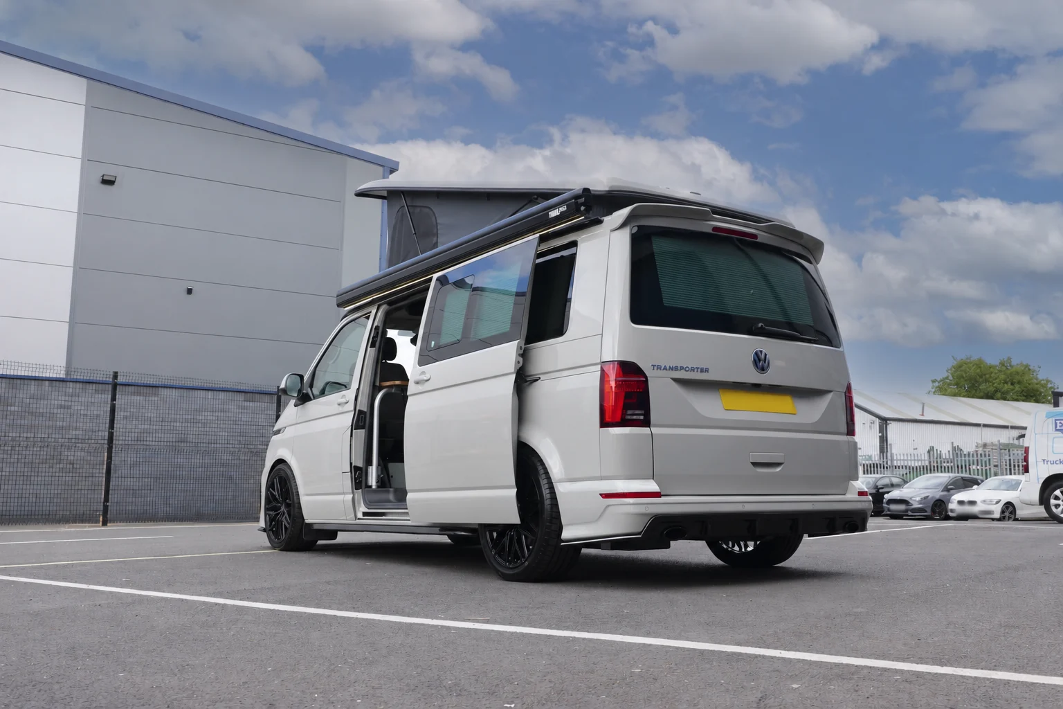 Rear three-quarter view of the Ascot Grey VW T6.1 with raised pop top and retracted awning