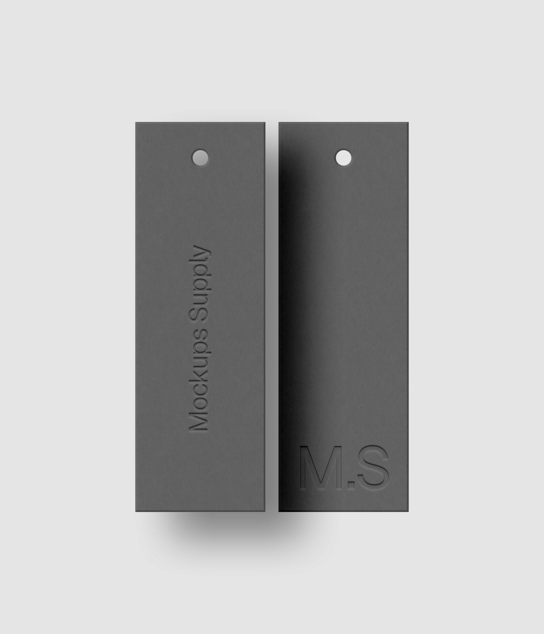 Two gray 1x3 clothing label mockup on white background with natural shadow depth and debossed text effect for Photoshop download psd