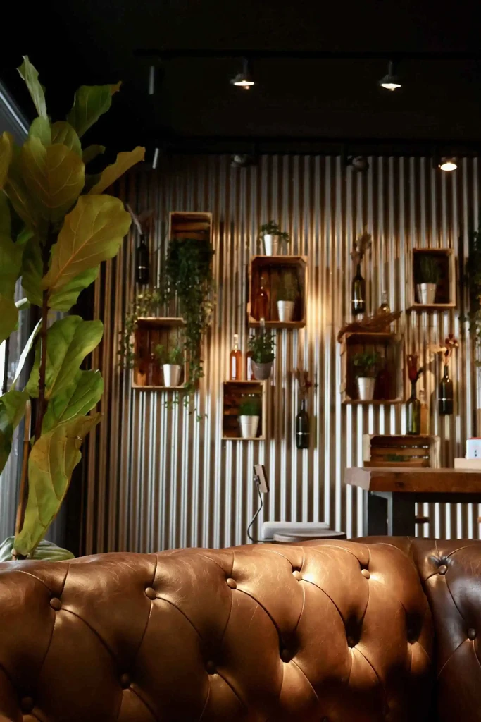 Gemütliche Lounge-Ecke im kAlps mit Ledersofa, Zimmerpflanzen und dekorativen Wandregalen.