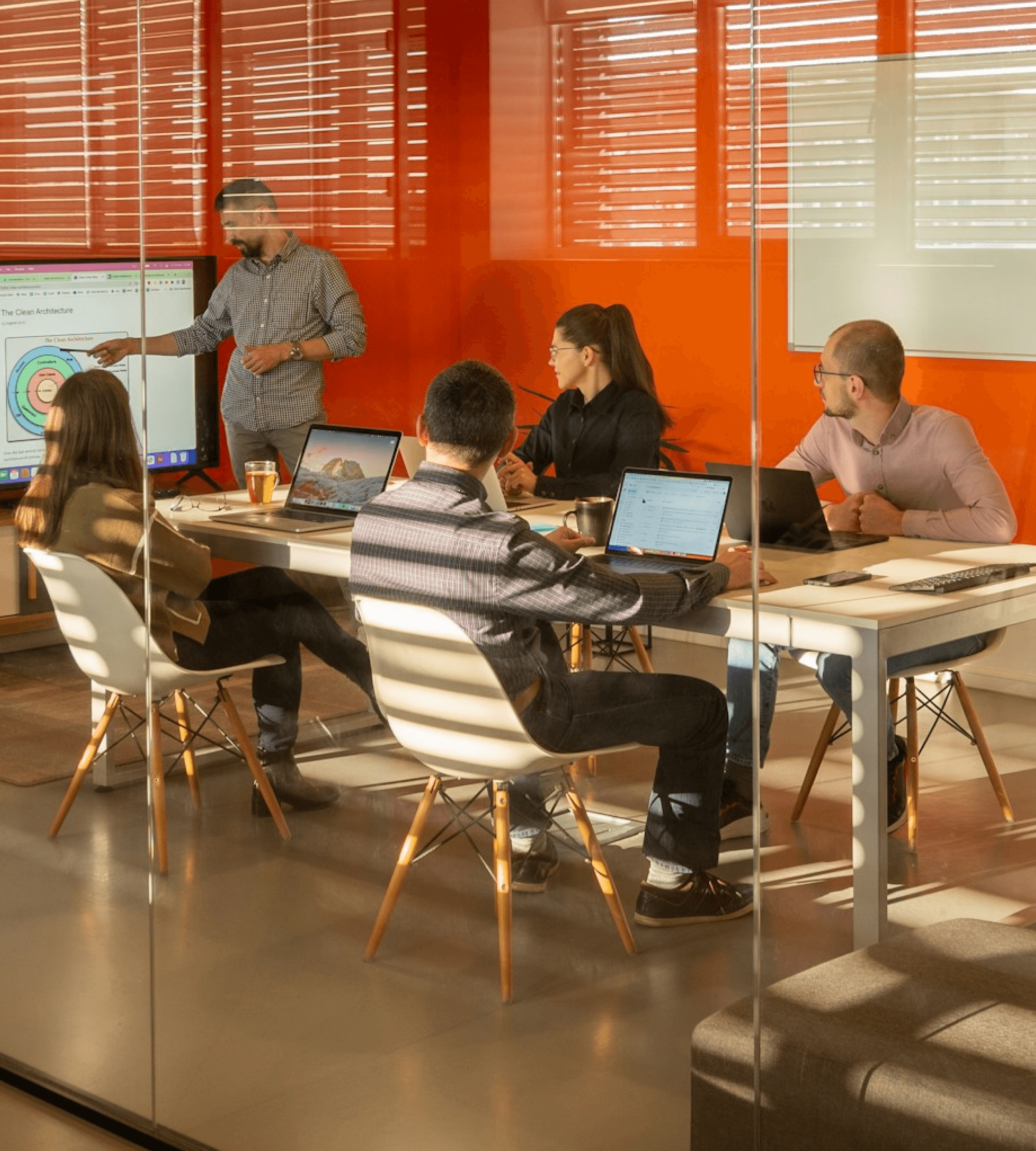 Team meeting in a bright office with a presenter at a screen.