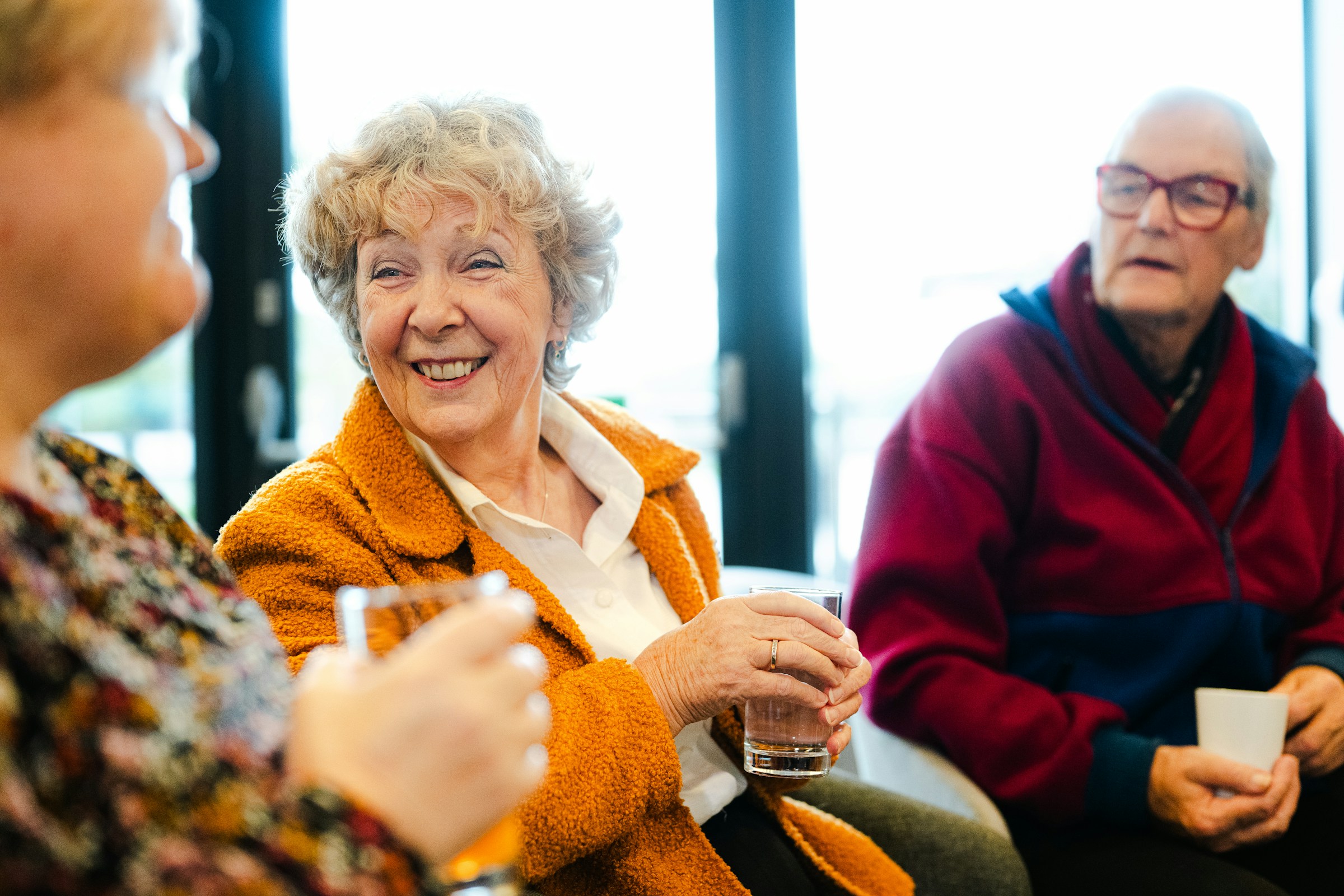 Two residents laughing together in the lounge at a senior living community