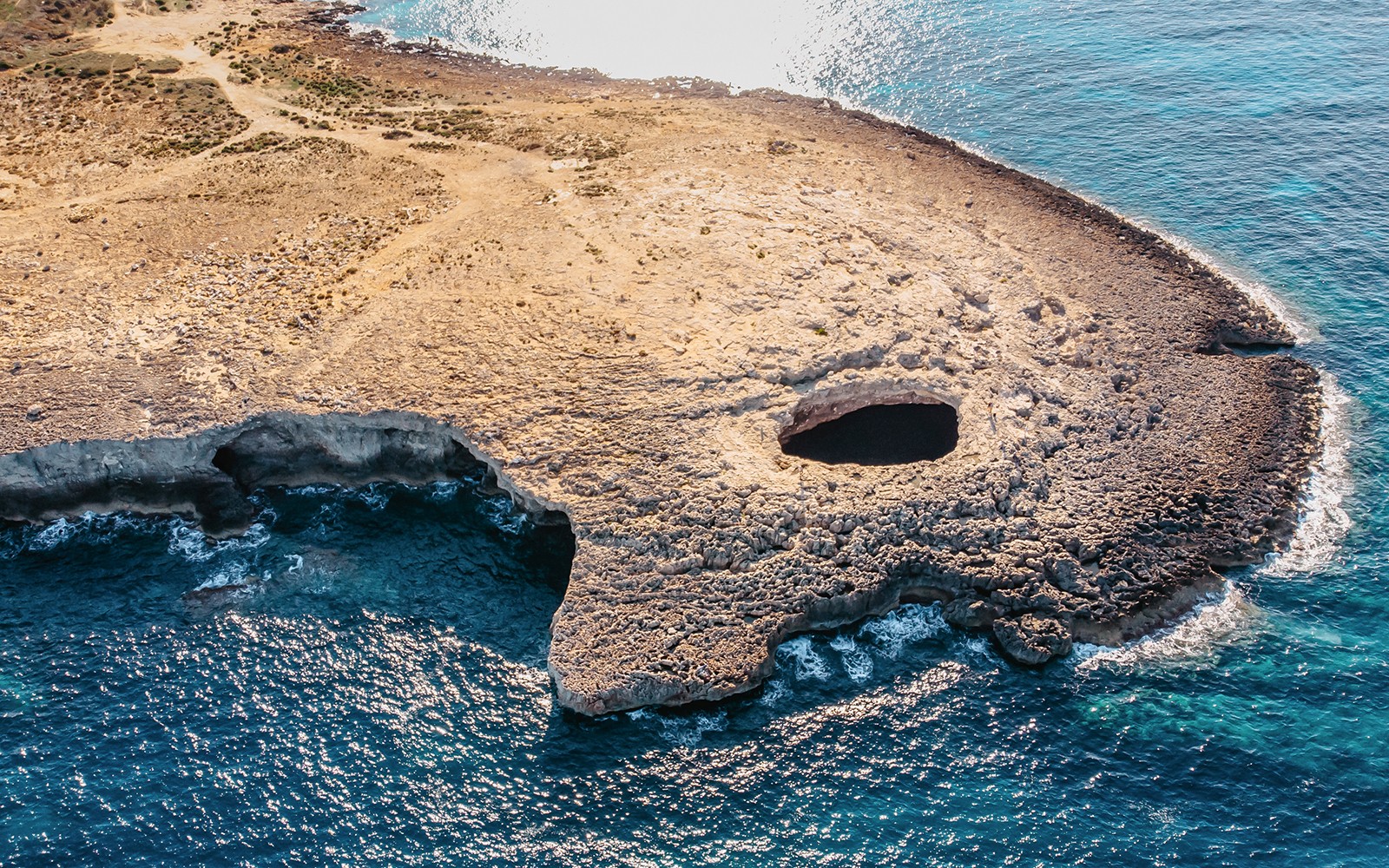 Aerial view of Ahrax fallen cave Coral Lagoon, Malta with surrounding coastline.