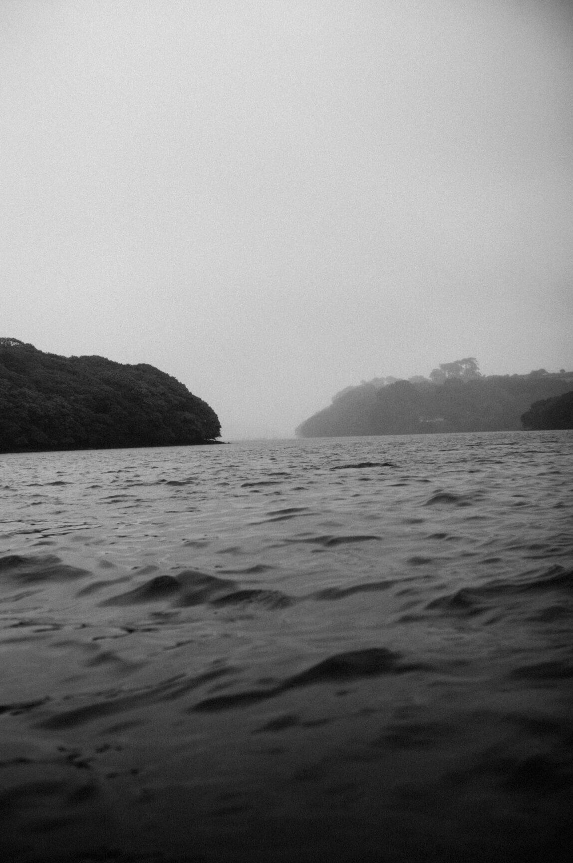 Black and white photo of the ocean with islands in the background