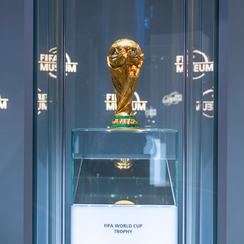 The FIFA World Cup trophy displayed in a glass case at the FIFA Museum, illuminated and prominently featured.