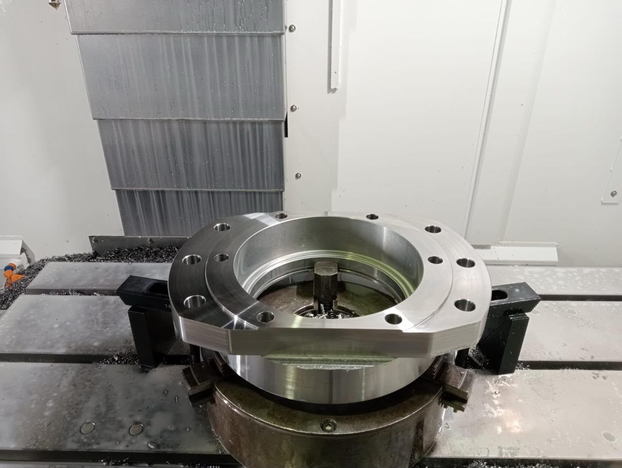 Precision machined metal flange mounted on a CNC lathe machine for inspection.