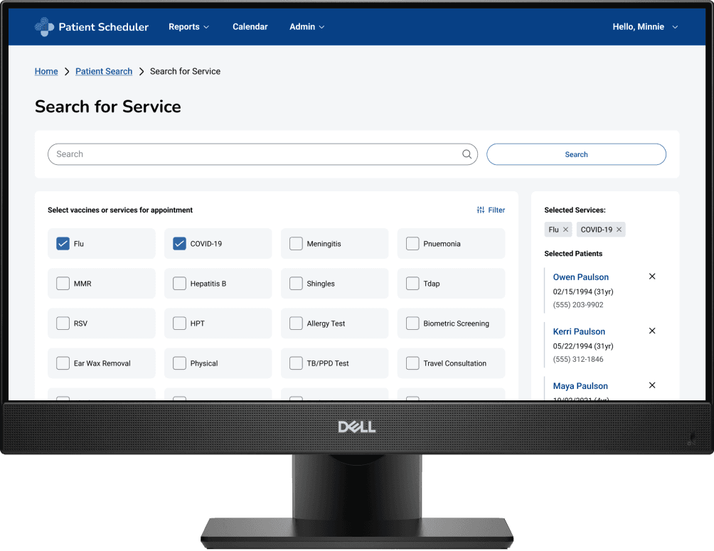 A computer monitor displays a patient scheduling interface with options for COVID-19, flu, and other vaccinations or services, emphasizing healthcare appointment management.