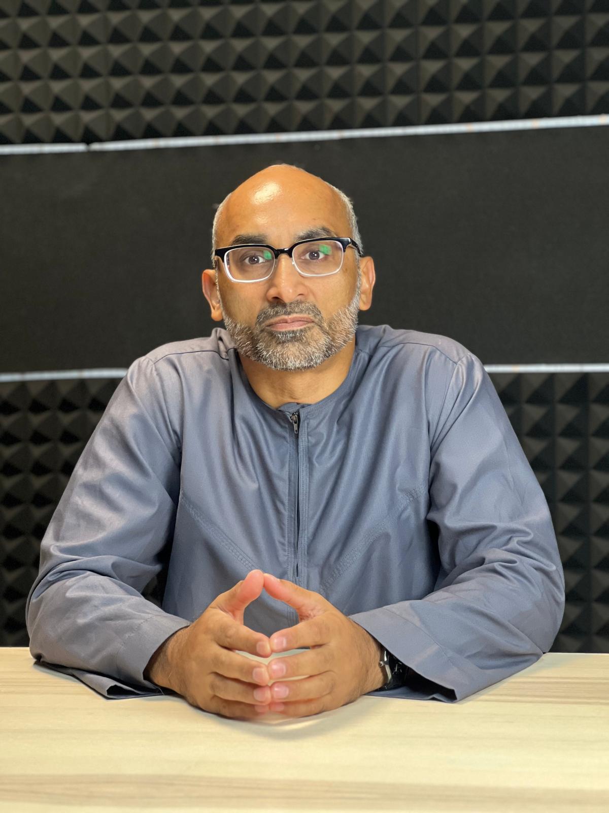 A young person with long, wavy hair sits in front of a plain background, looking directly at the camera.