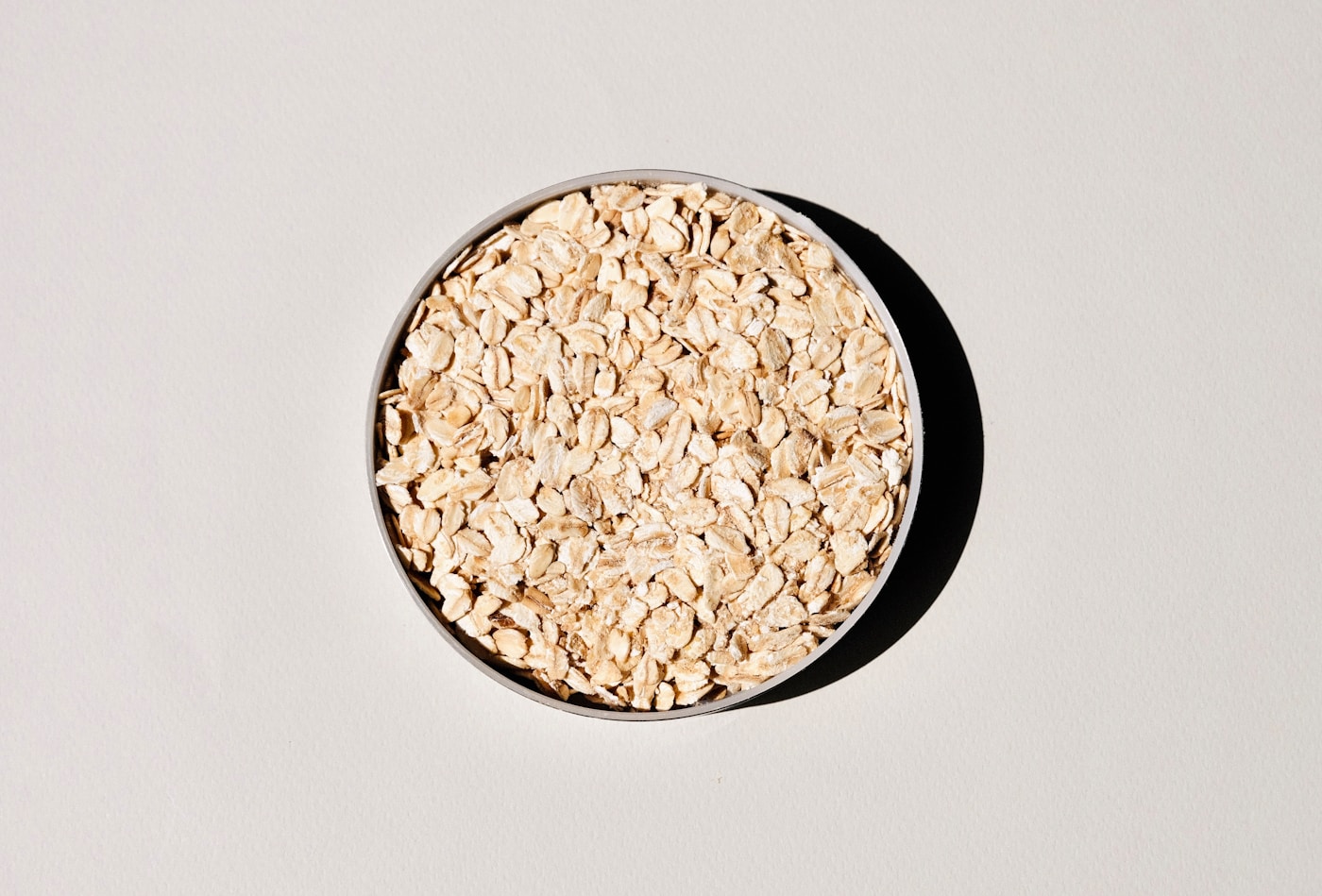 A bowl of rolled oats, a soluble-fiber-rich food, viewed from above on a pale background
