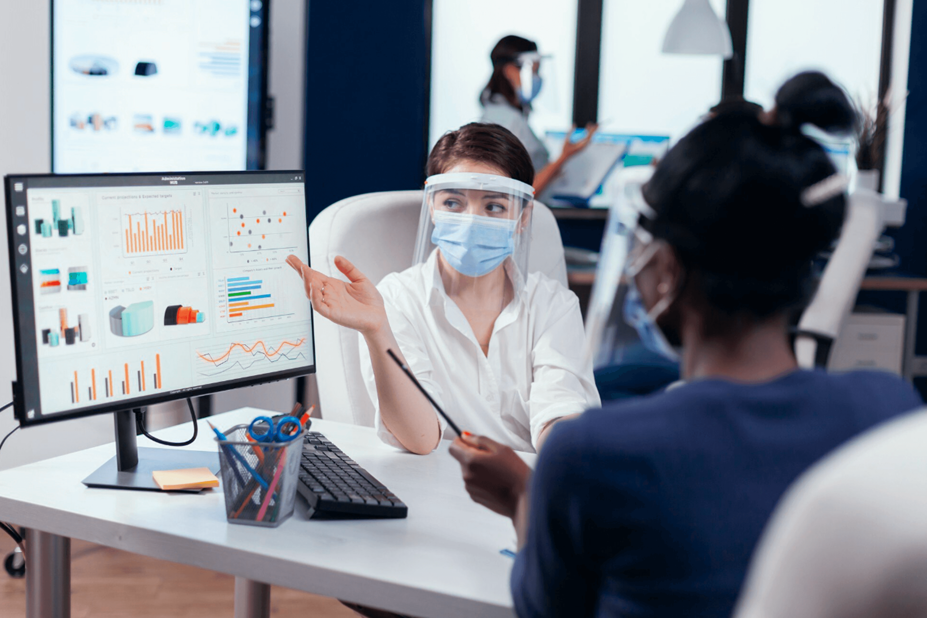 Healthcare analyst reviewing data exchange dashboards with a colleague, illustrating TEFCA-driven interoperability strategy and nationwide health information sharing.