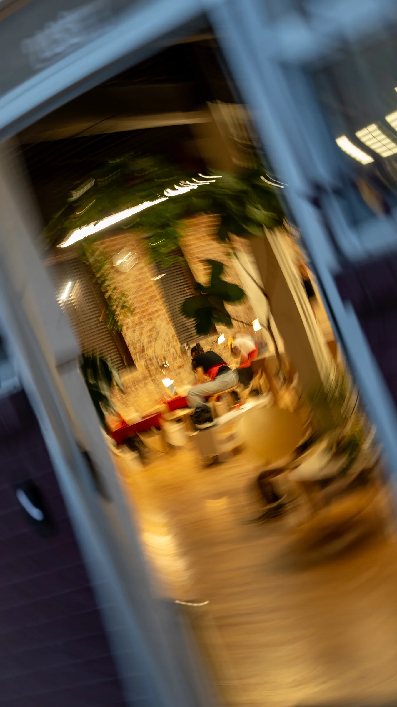 Tilted, motion-blurred view through the open door into the warm-lit studio