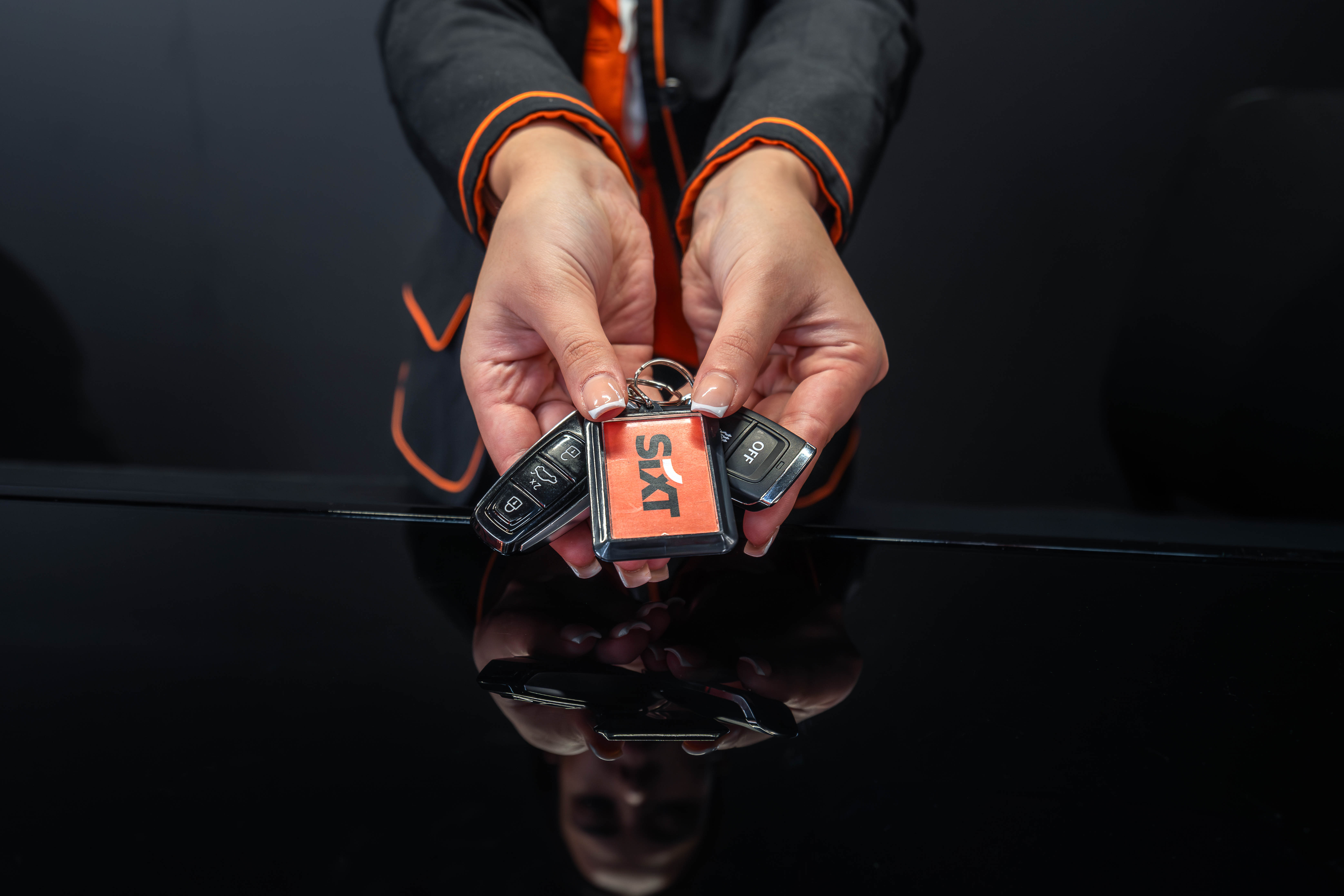 Twee handen houden een kleurrijke verzameling pokerspelden vast boven een reflecterend zwart oppervlak, met een donkere achtergrond.