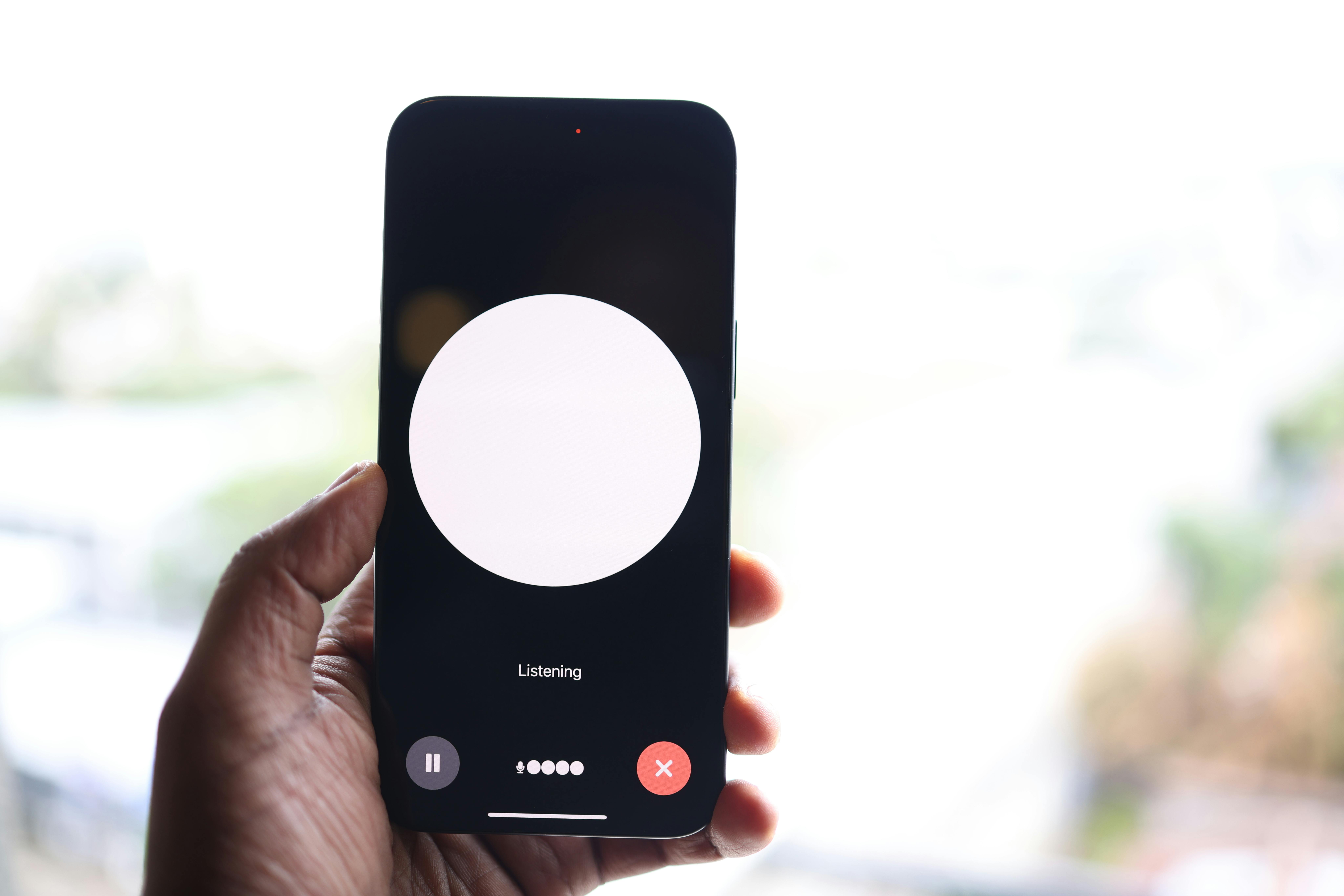 A Person Holding a Smartphone with an app that says "listening"