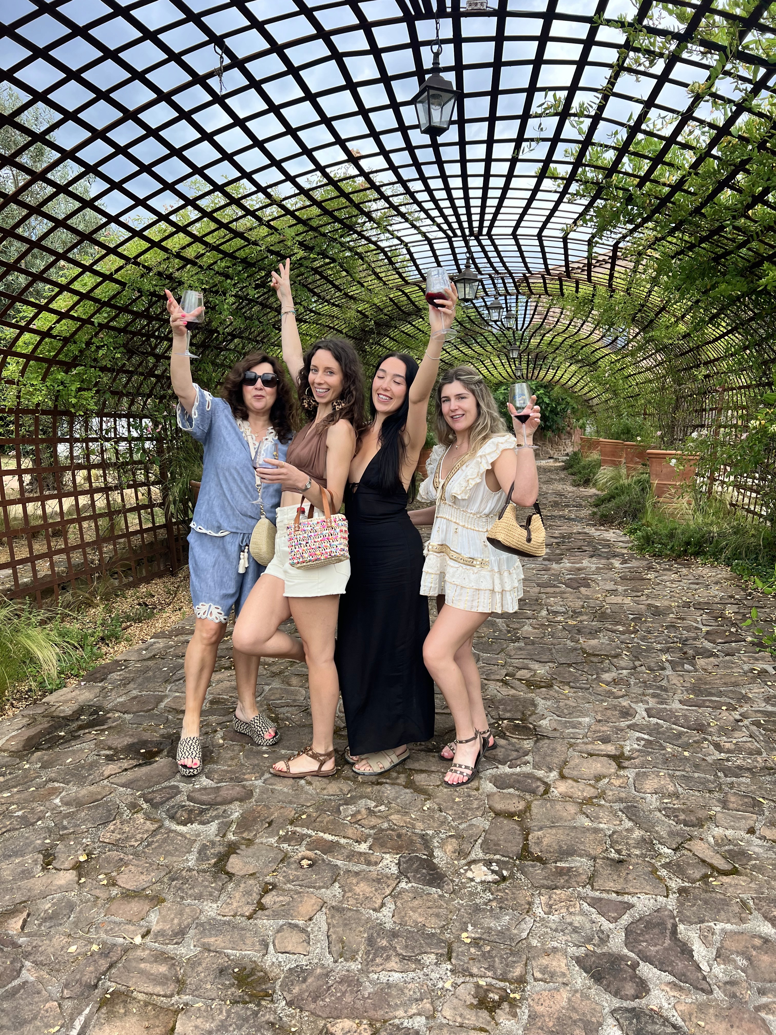 Friends raising glasses beneath a vine-covered pergola