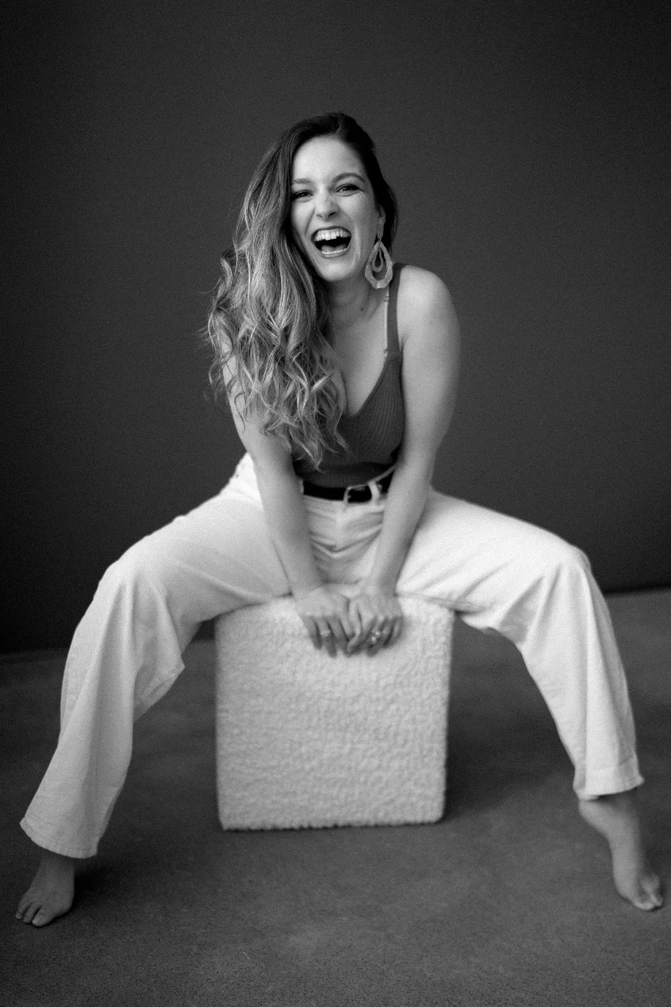 Laughing woman in white pants, embracing self-love in Swiss boudoir photography.