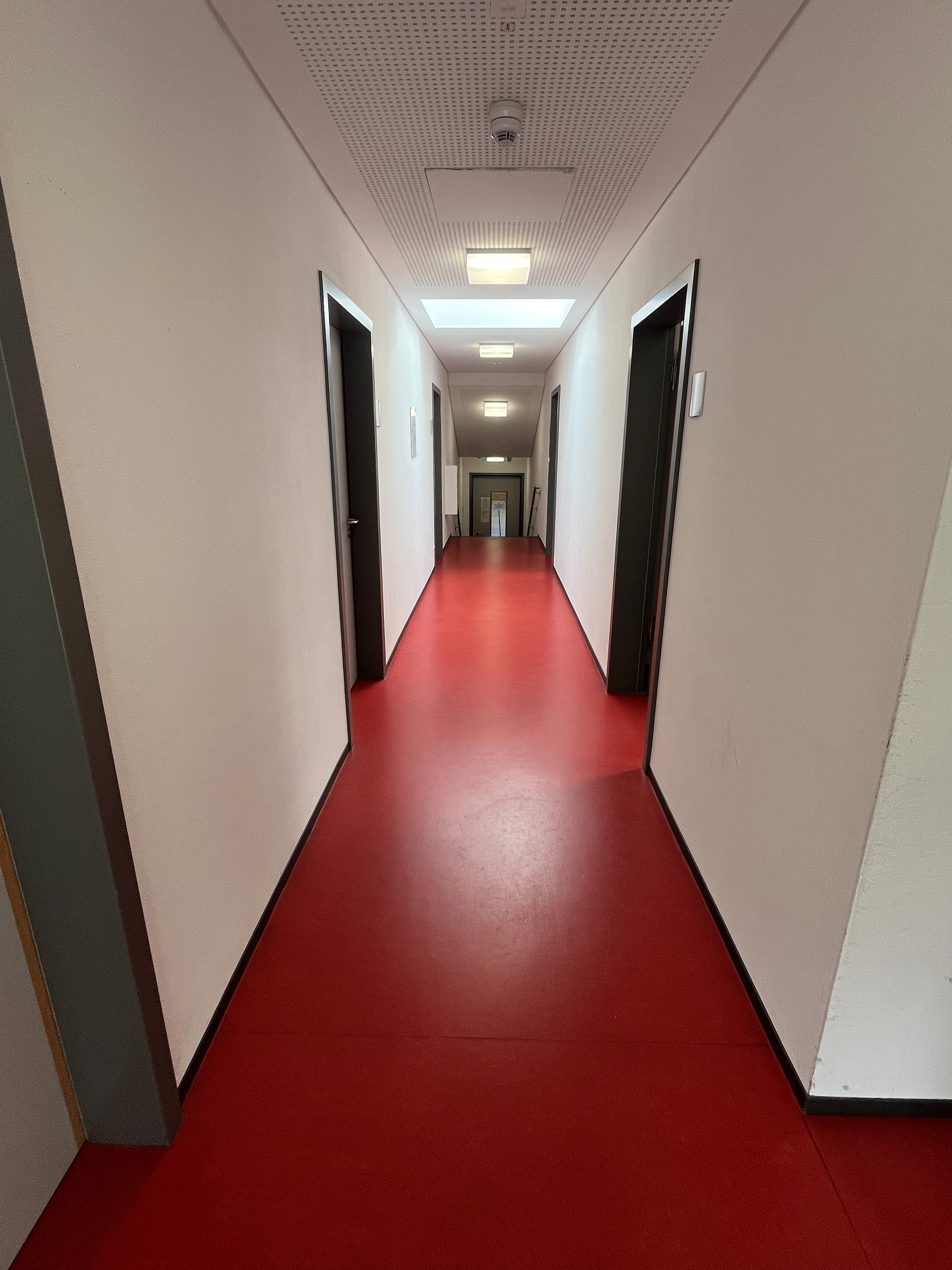 Roter Fußboden und weiße Wände im Sporthallenflur