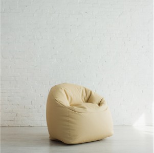 En beige saccosäckstol mot en vit tegelvägg