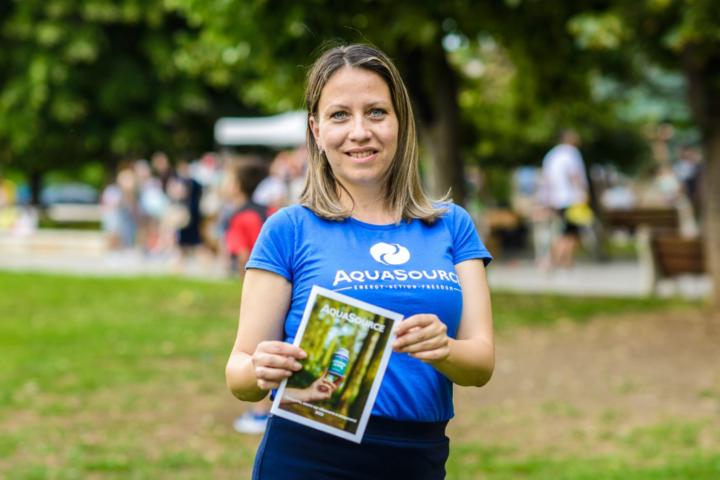 Young man with glasses in a gray hoodie, sitting in front of a computer screen with an orange background.