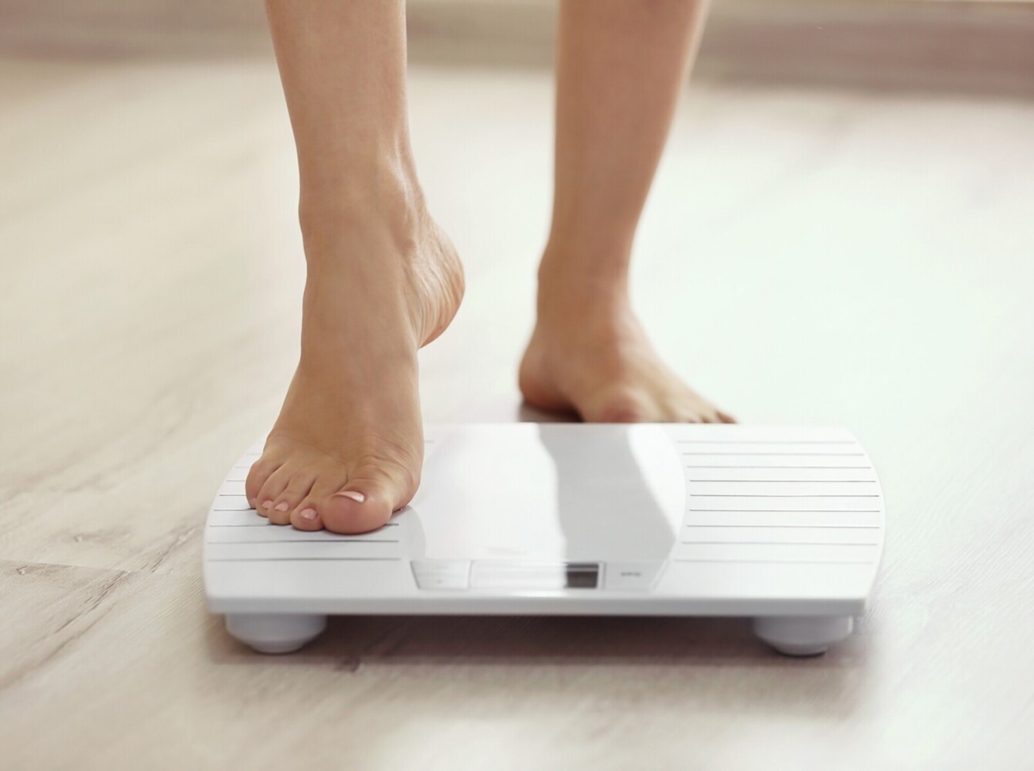 woman stepping on a scale after using a steam room for losing weight