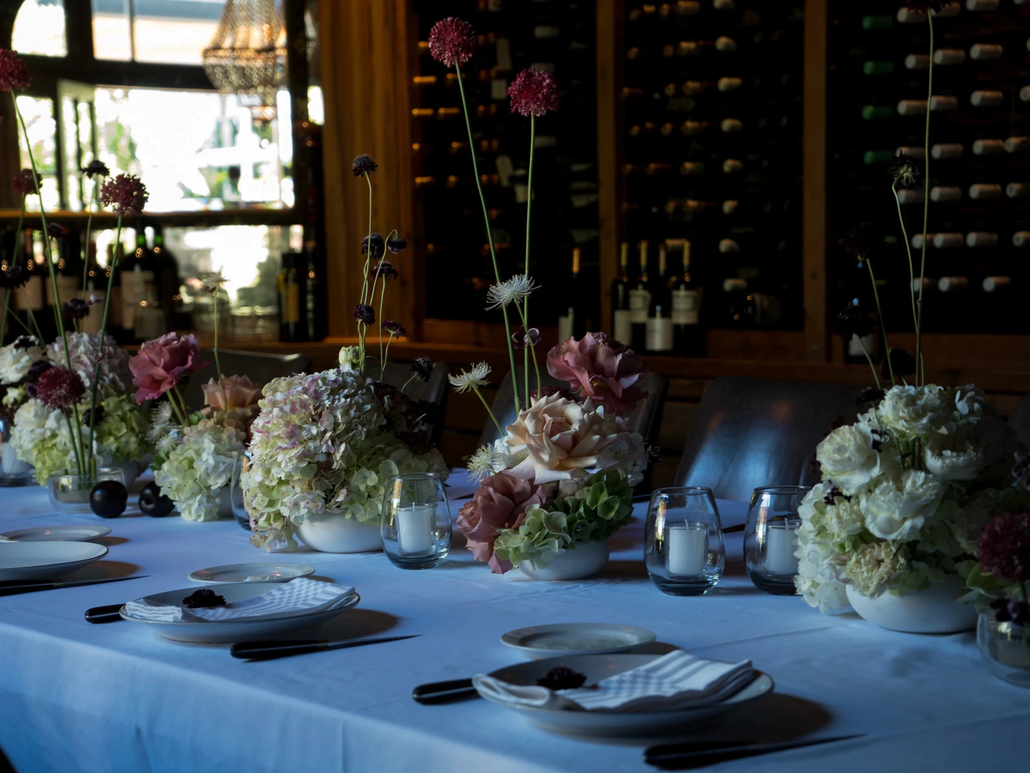 Decoración de mesa elegante con vajilla blanca, velas y flores etéreas en el salón interior de Gardiner.