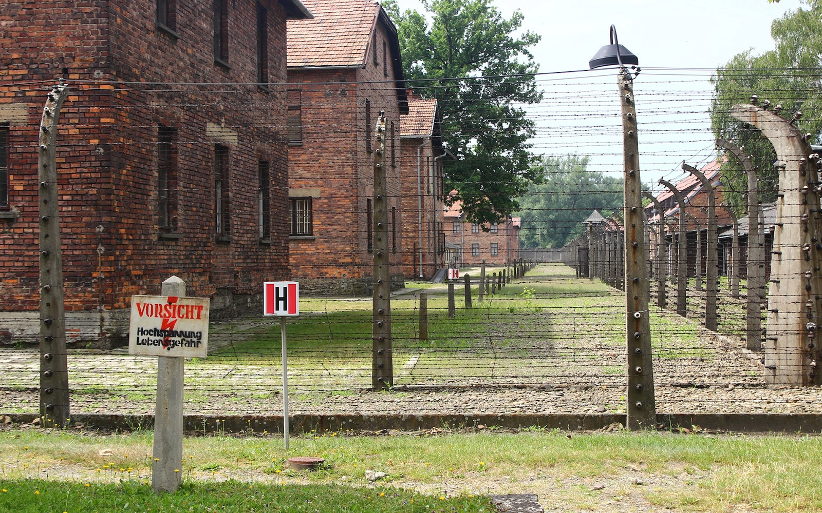 Recinto di filo spinato ed edifici in mattoni presso il sottocampo di Auschwitz, Polonia.
