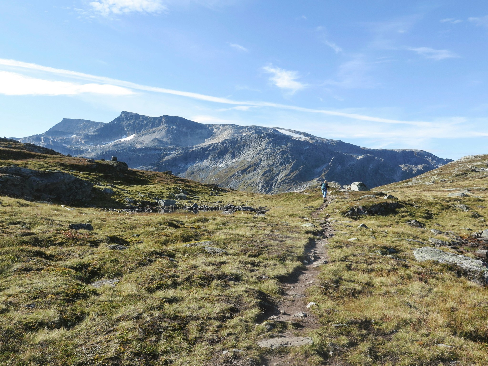A solitary hiker walks across a mountainous landscape in Norway's Lofoten Islands.