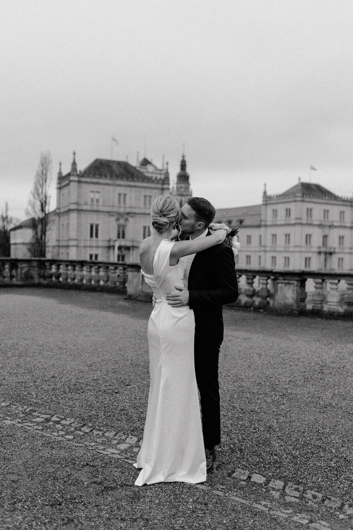 Zeitloses Schwarz-Weiß-Foto eines Brautpaares vor einer Schloss-Kulisse – professionelle Hochzeitsreportage von Selina Fröhlich.