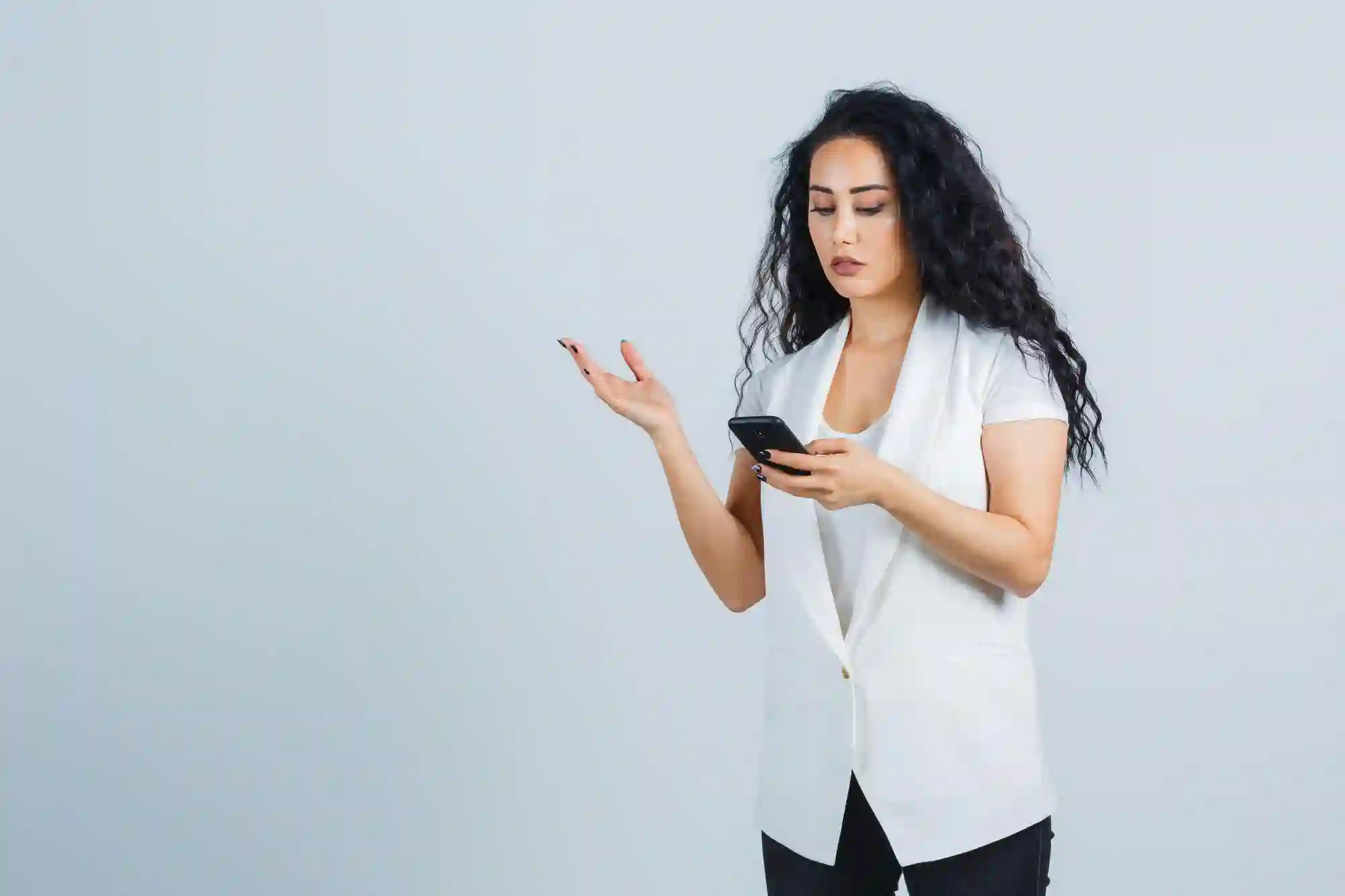 A professional woman looking at her smartphone, representing modern digital communication and mobile business management in the workplace.